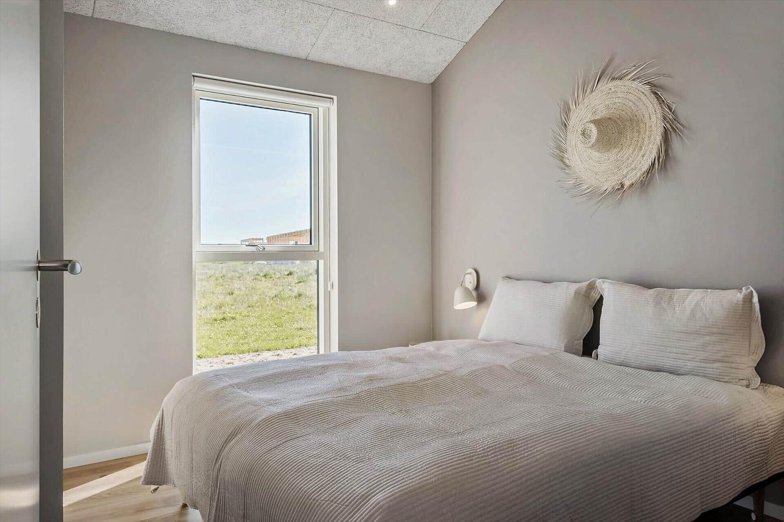 Schlafzimmer mit Bett, Fenster und Wanddekoration.