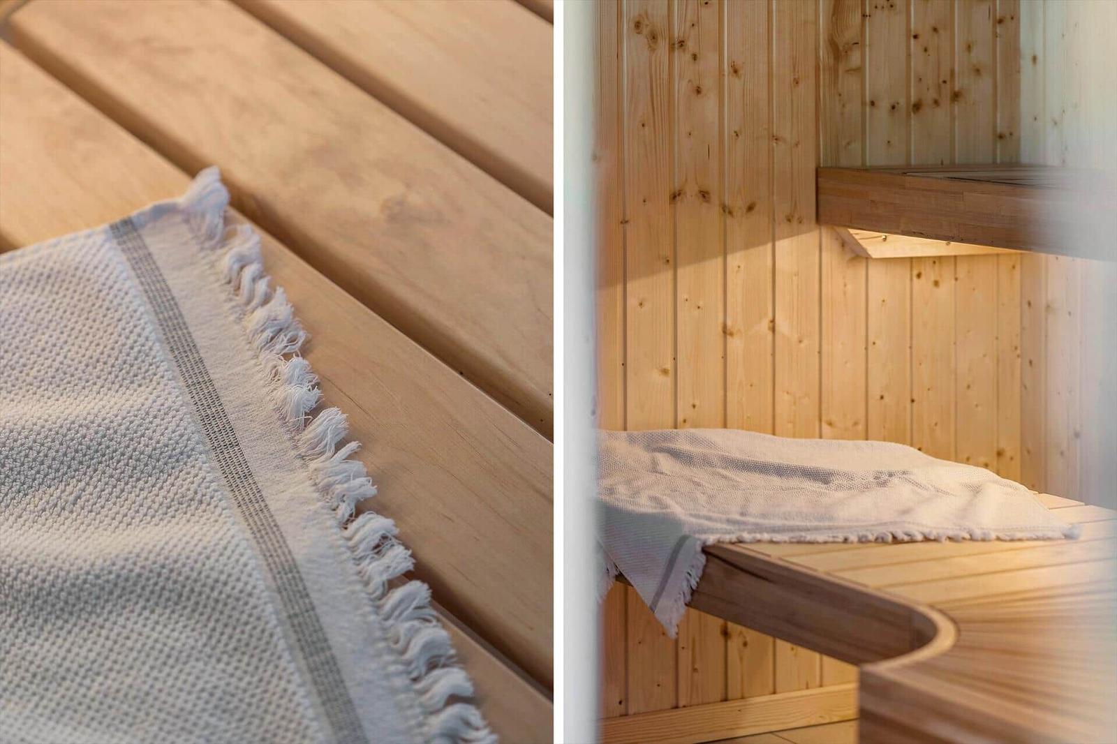 Holzsauna mit Bank und Deckenboden. Weiße Decke liegt auf der Bank.