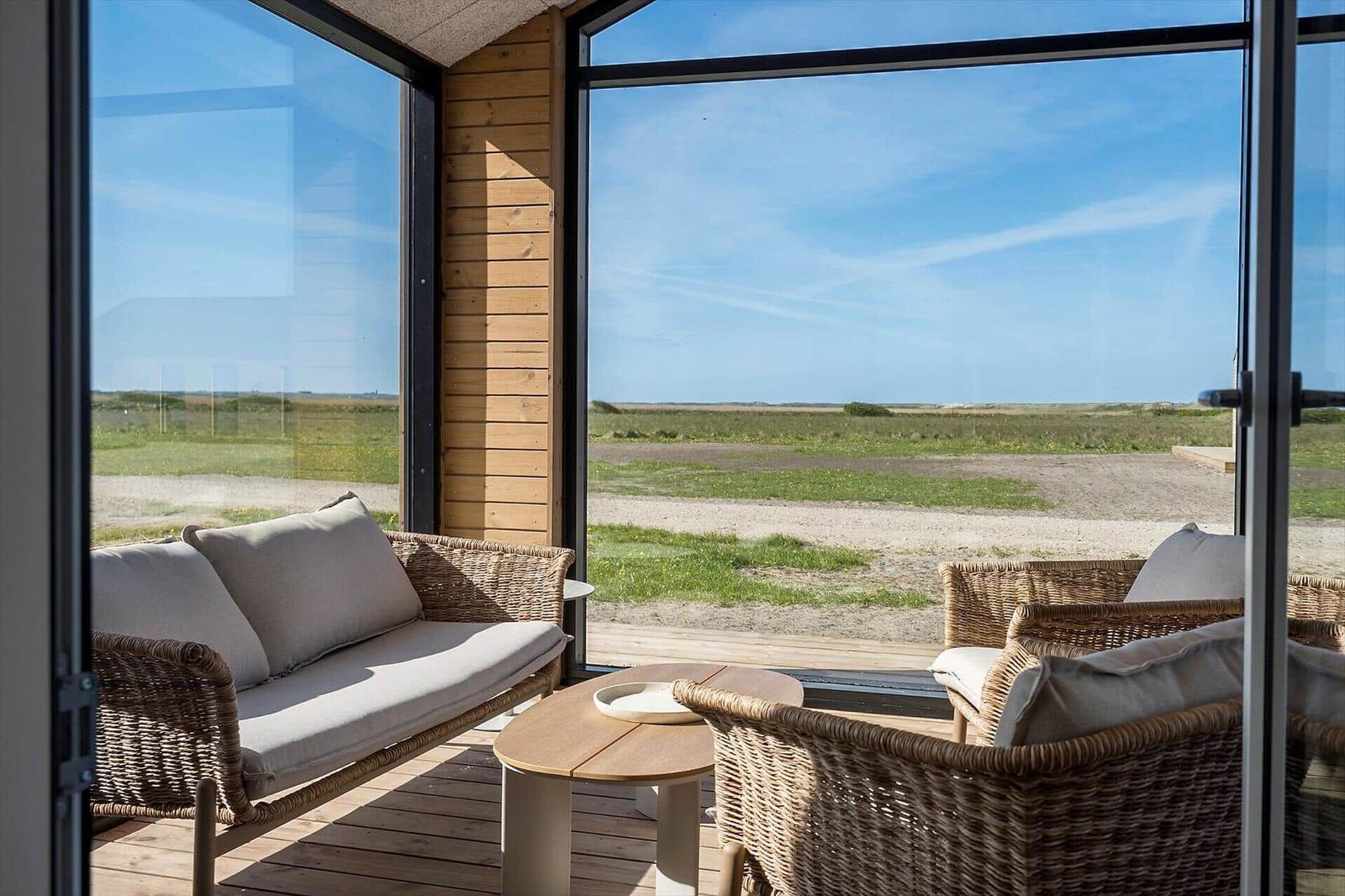 Terrasse mit Sitzgruppe und Blick auf Grasland und Himmel.