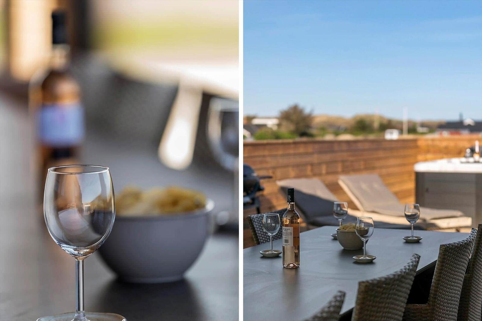 Tisch mit Wein und Chips auf Terrasse mit Liegen und Blick auf Landschaft.