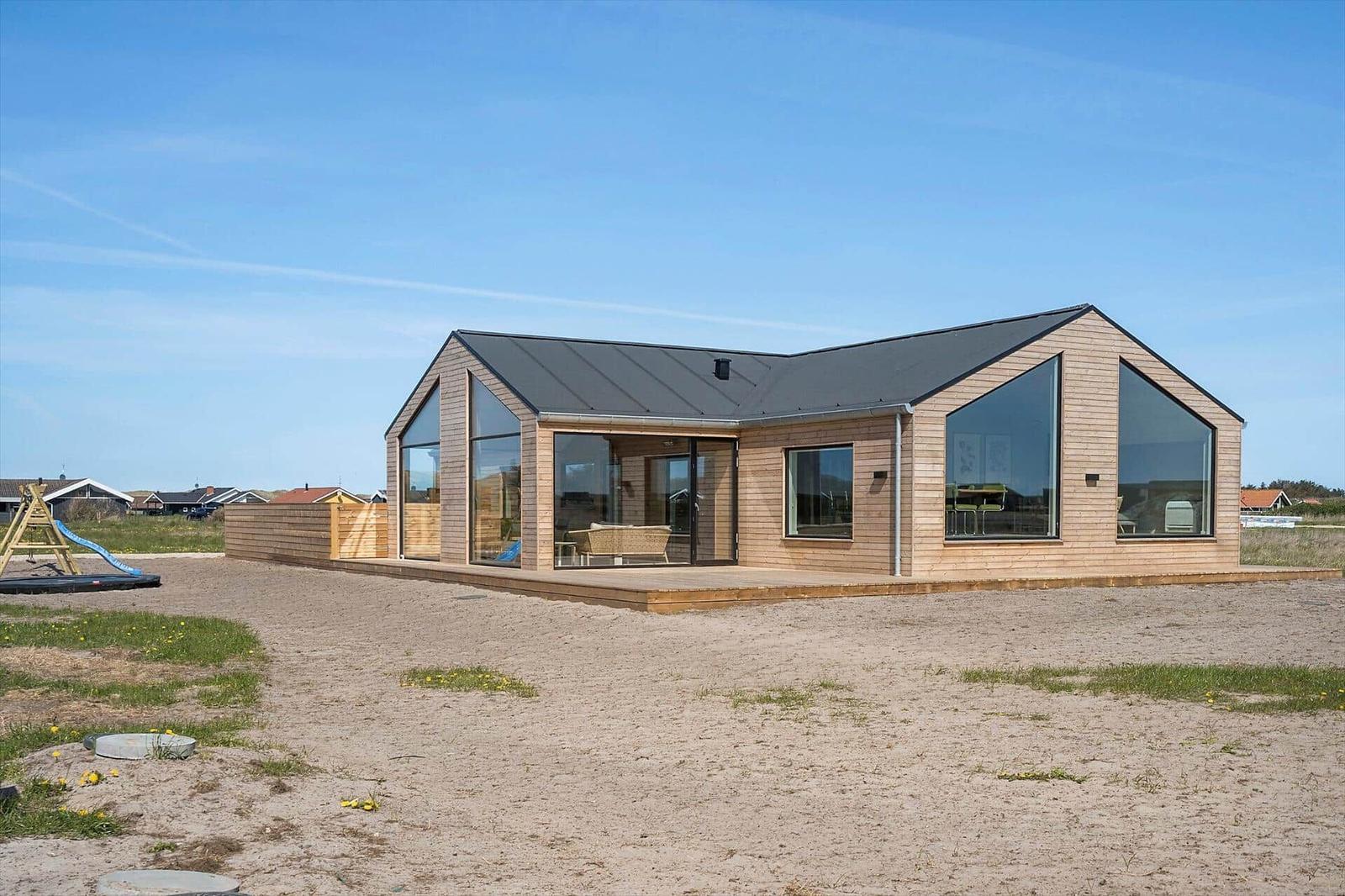 Moderne Holzhütte mit großem Glasbereich und Terrasse im Sand