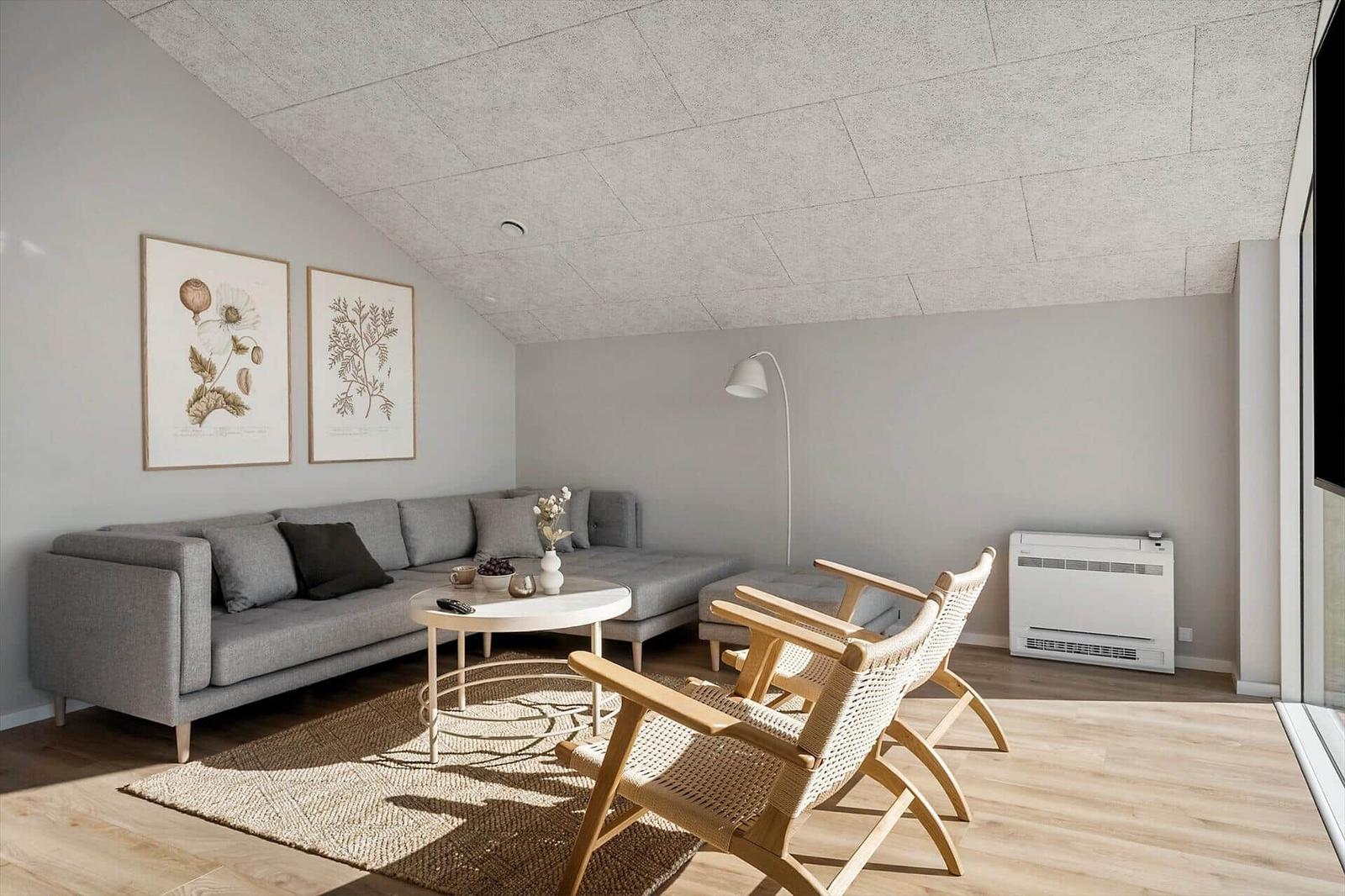 Ein Wohnzimmer mit grauem Sofa, zwei Holzstühlen und einer runden Tischplatte.