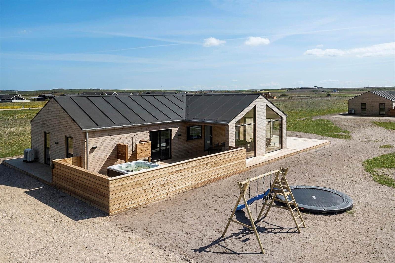 Moderne Ferienhaus mit Whirlpool, Spielplatz und Trampolin auf freiem Grund.
