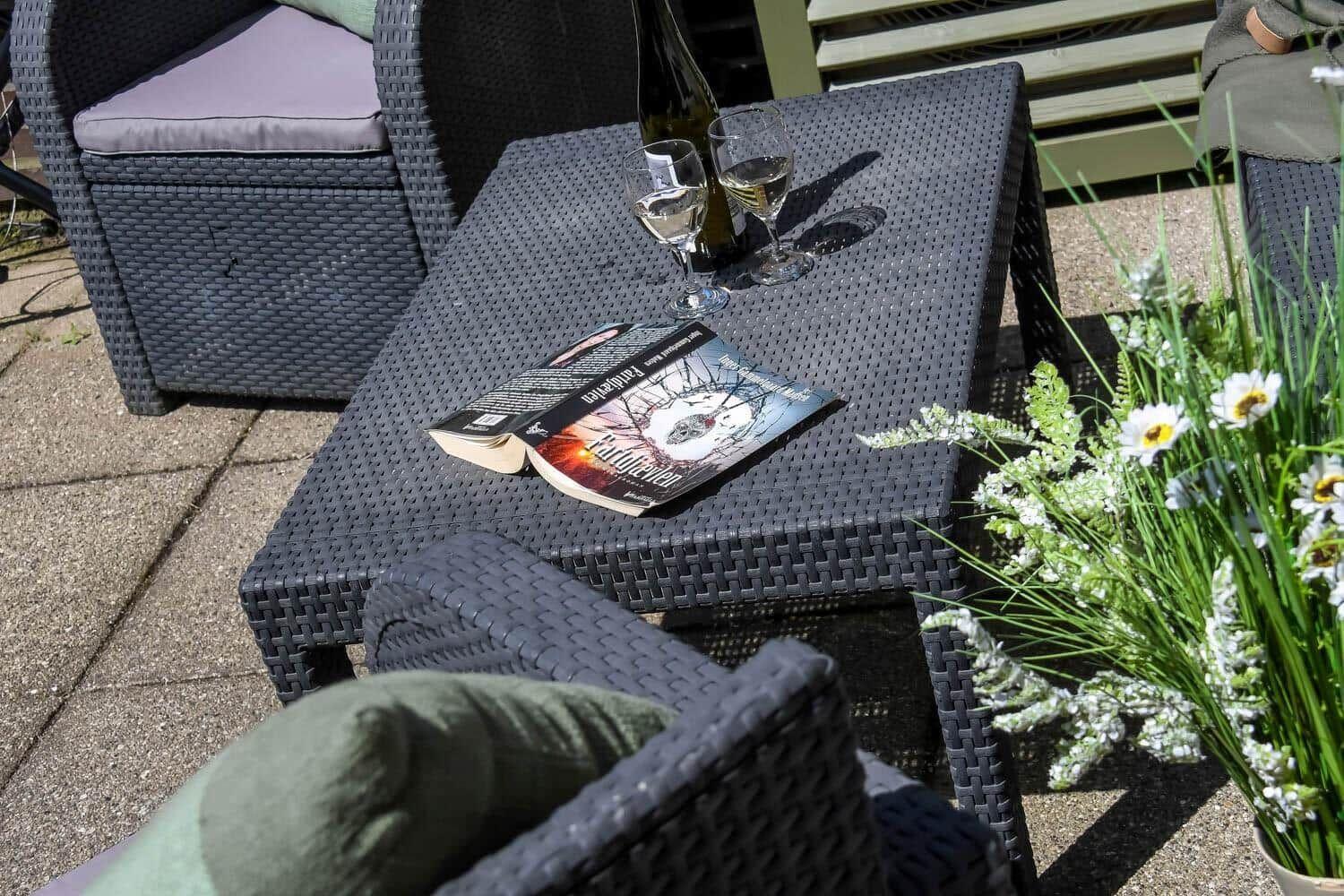 Außenbereich mit Tisch, Stühlen, Wein und Blumen.