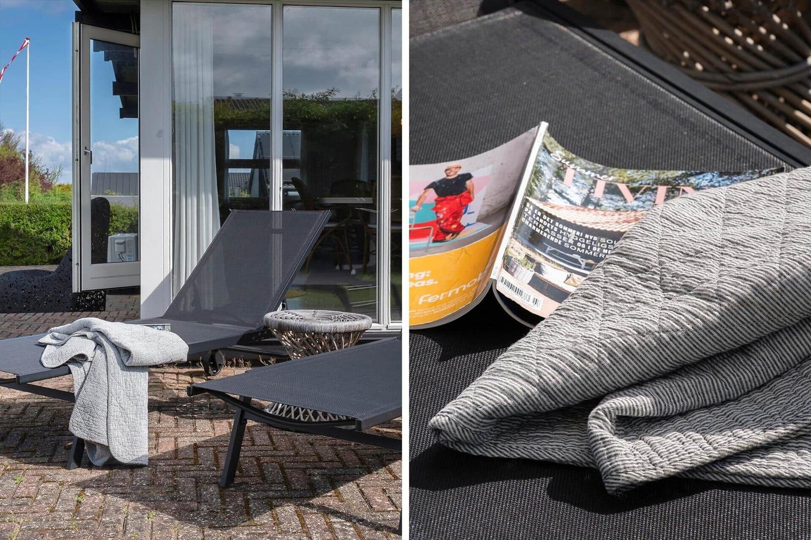 Terrasse mit Liegestühlen und Zeitschriften. Blick in das Haus durch Glastüren.