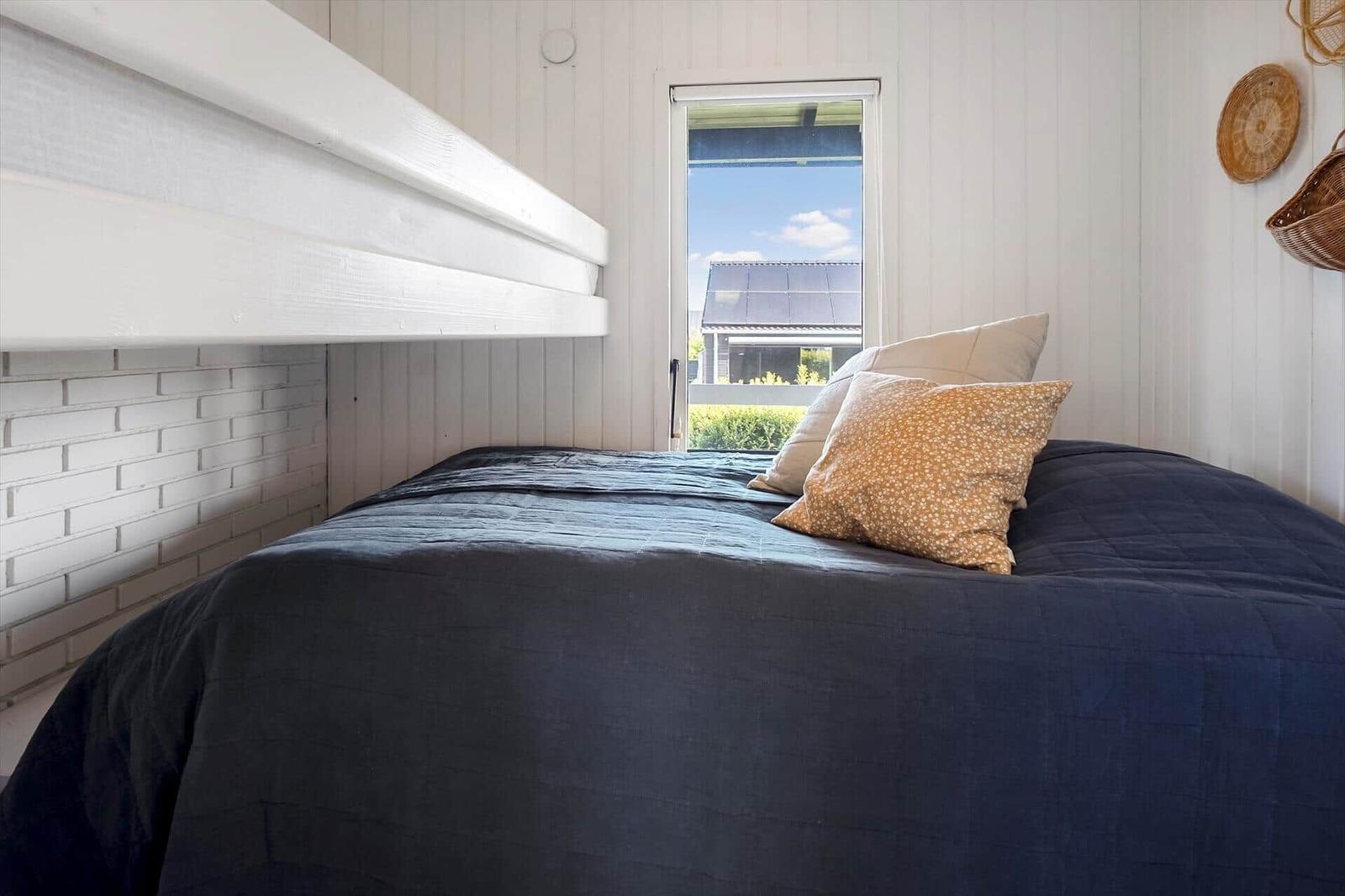 Schlafzimmer mit Doppelbett, Fenster und Wanddekoration.