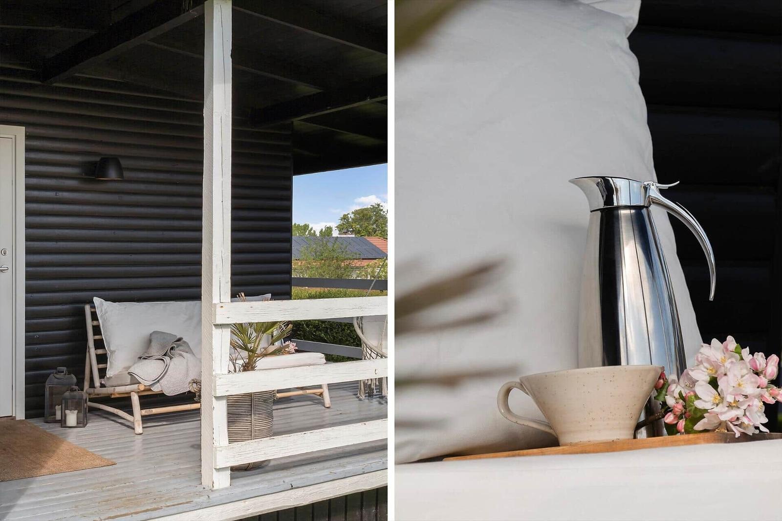 Terrasse mit Liege und Blick auf Garten. Tisch mit Kanne, Tasse und Blumen.