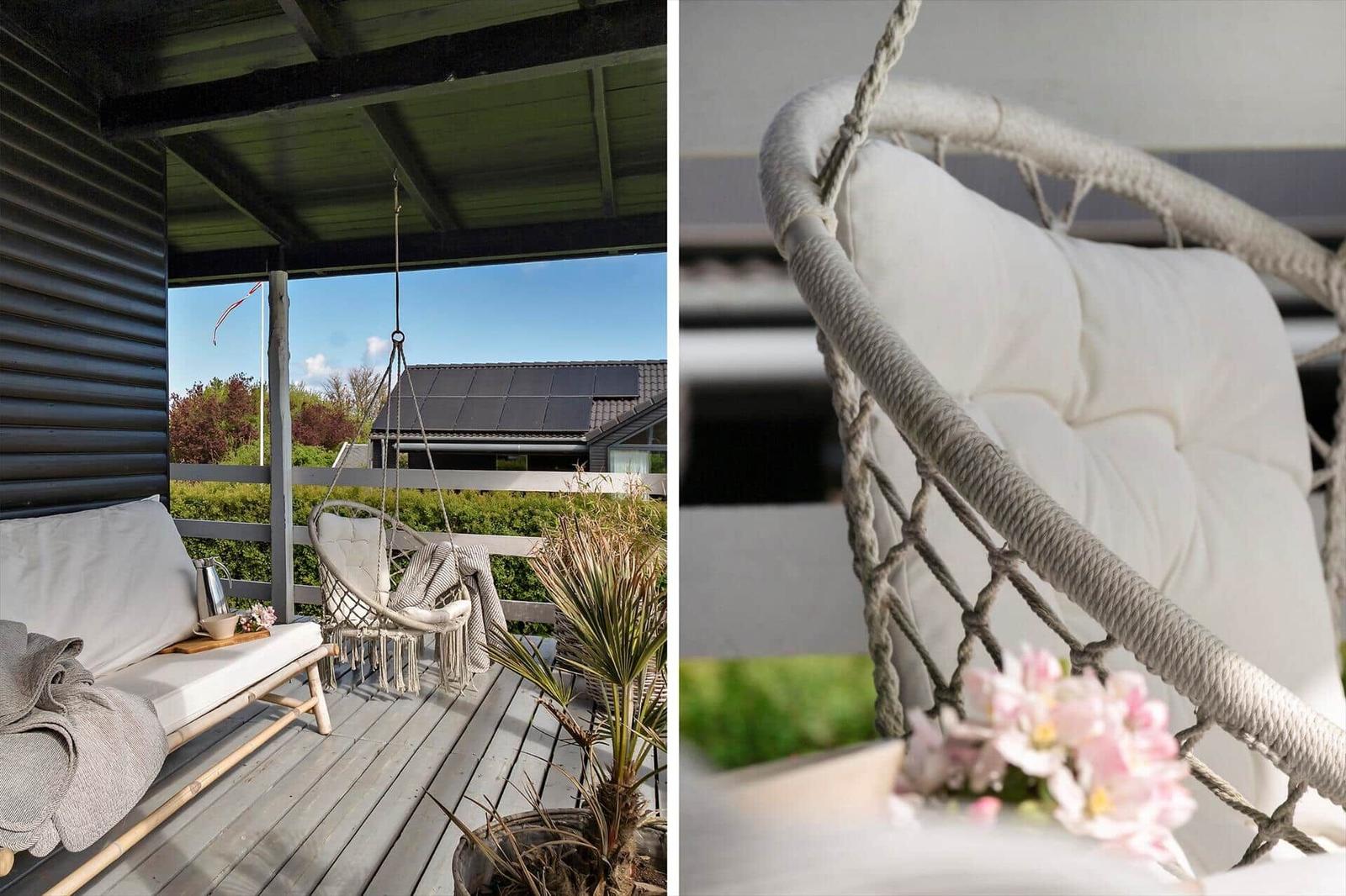 Terrasse mit Hängesessel und Sofa unter Dach. Blick auf Garten und Nachbarhaus.