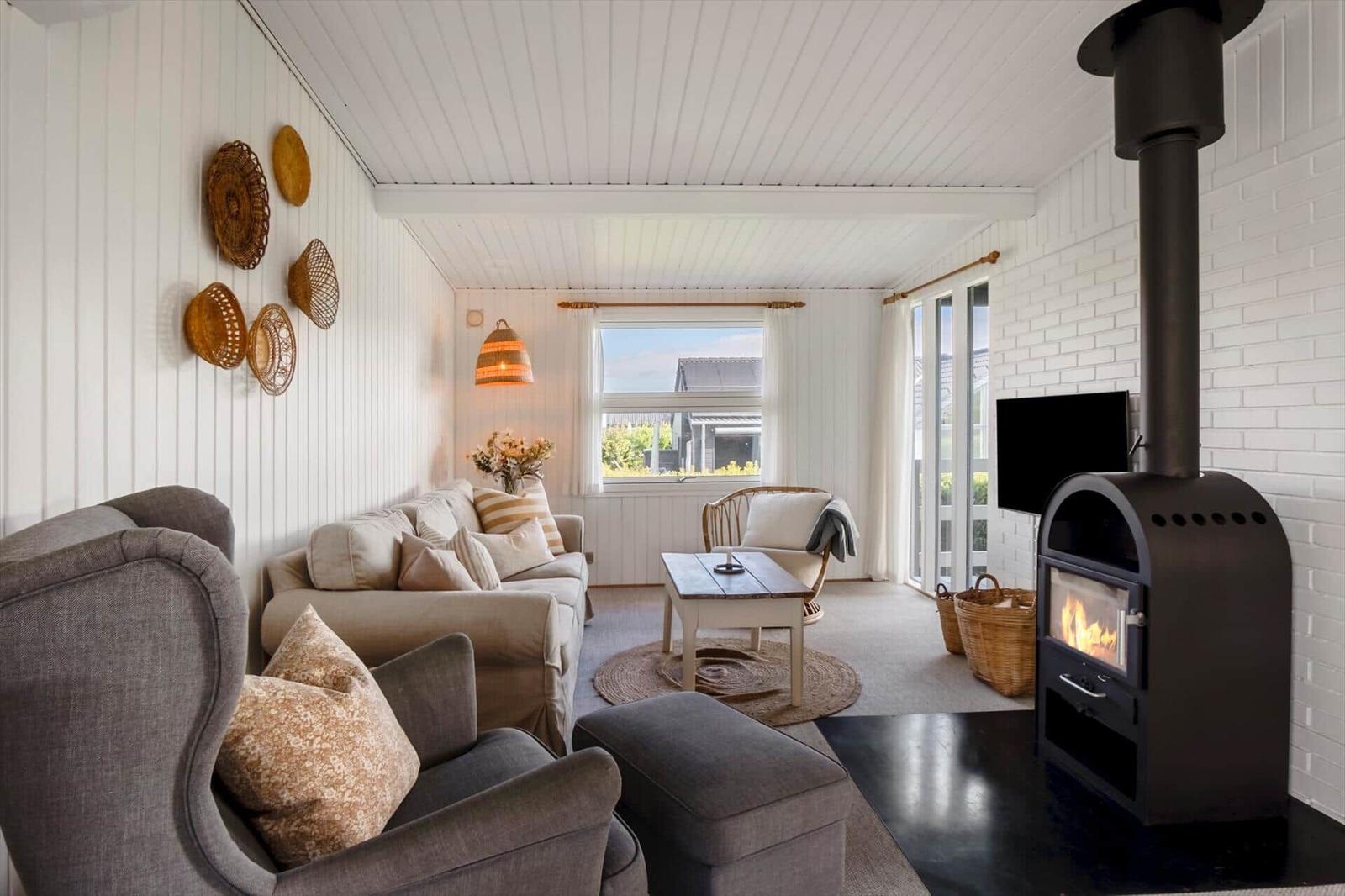 Wohnzimmer mit Sofa, Sessel, Kamin und Fenster zur Aussicht.