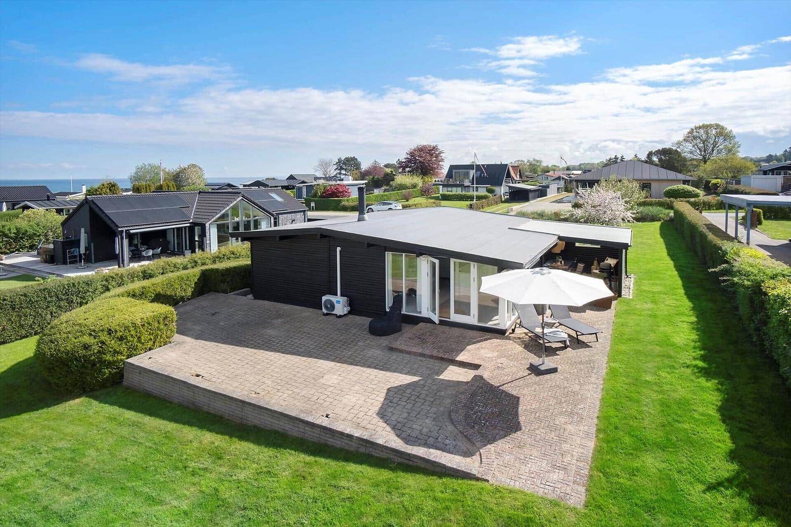 Moderne Villa mit Terrasse, Garten und Meerblick. Weiße Sonnenschirm und Liegen.