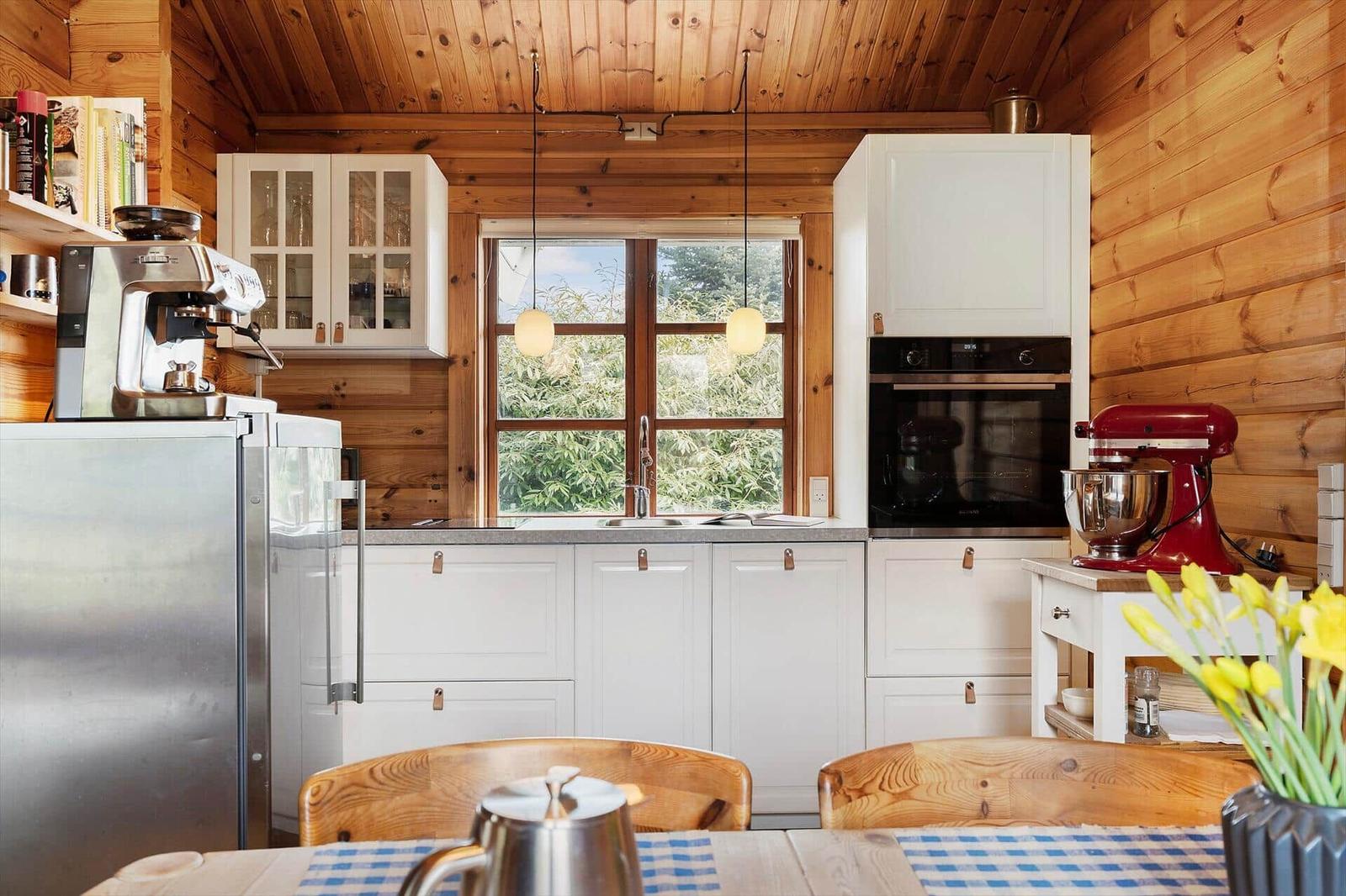 Kitchen with wooden walls, white cabinets, and red stand mixer.