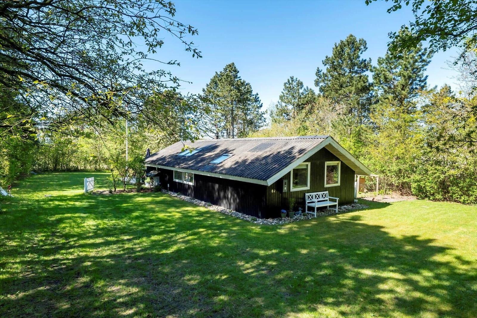 A dark green house with white window frames and skylights stands on a green lawn.