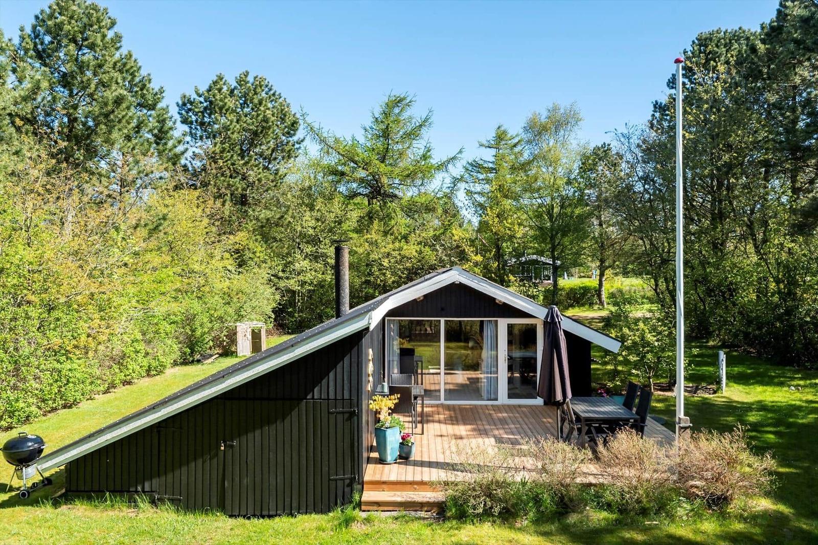 Wooden cabin with terrace, grill, and garden near forest
