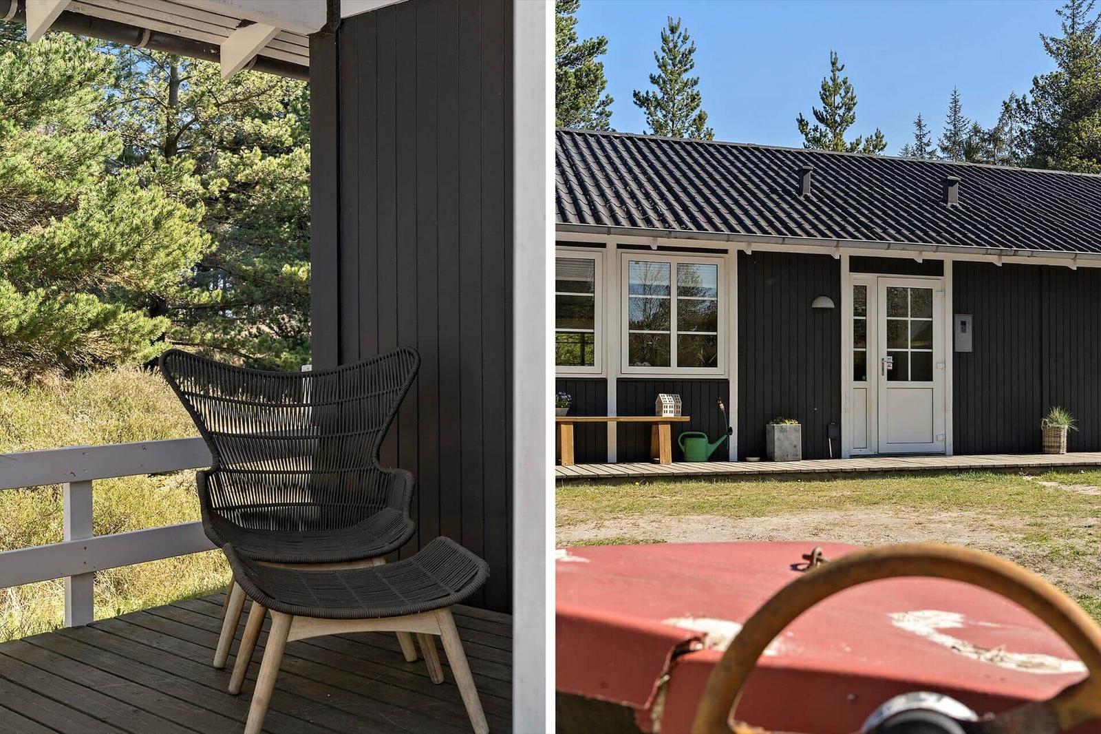 Schwarze Holzhütte mit Terrasse und Stuhl. Grünzeug im Hintergrund.