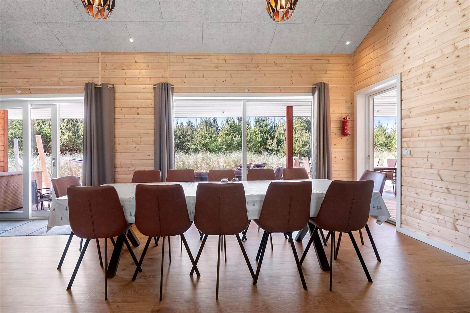 Großer Essbereich mit Holzwand und Tisch für acht Personen.