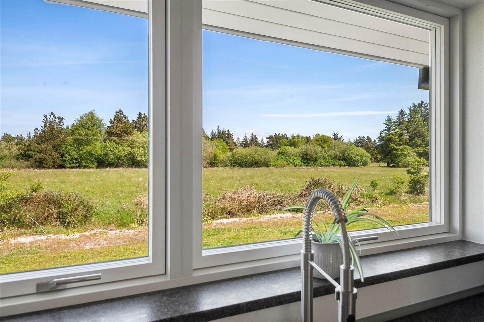 Küchenfenster mit Blick auf grünes Feld und Bäume