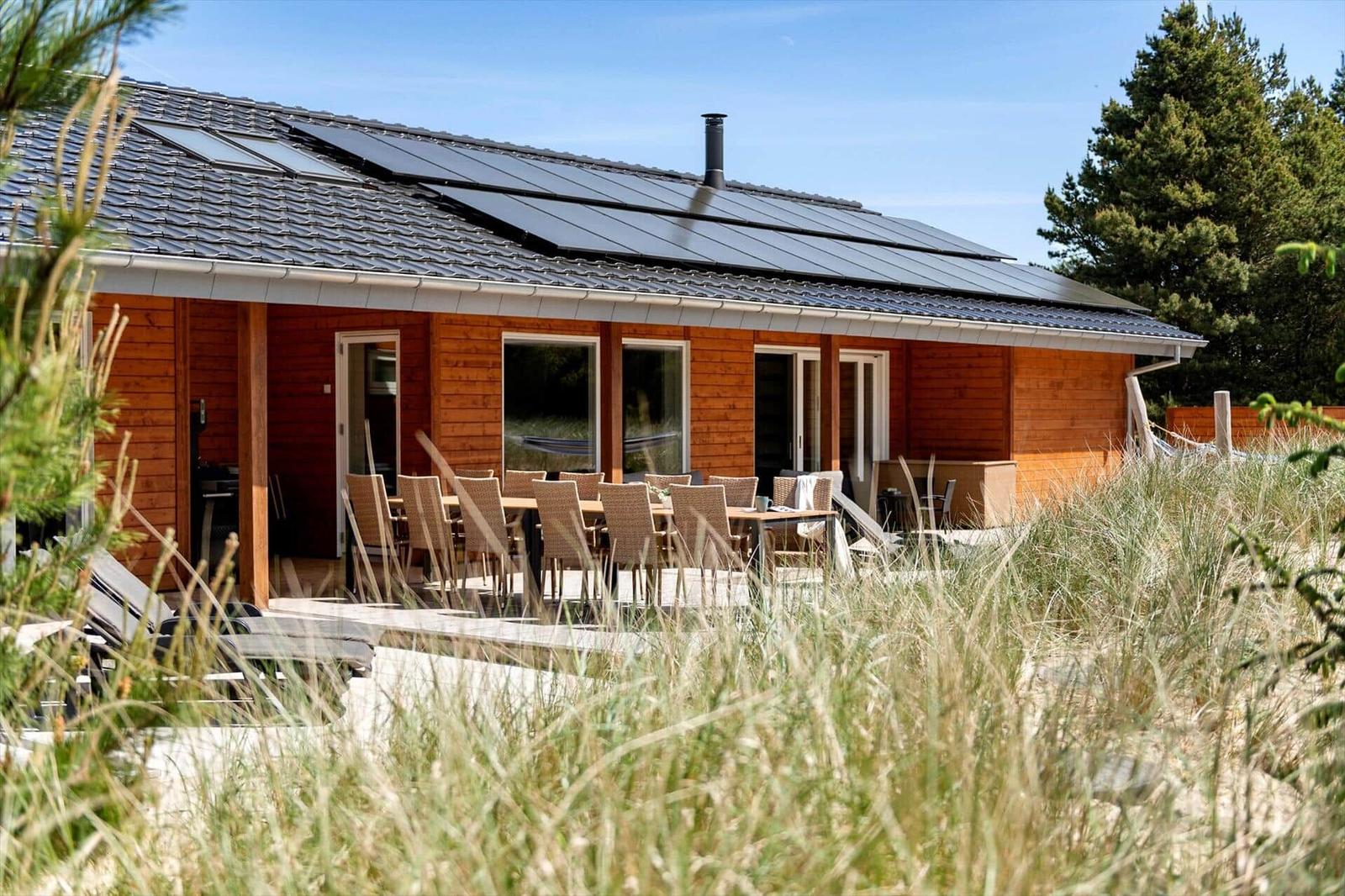 Holzhaus mit Solaranlage und Terrasse mit Tisch und Stühlen.