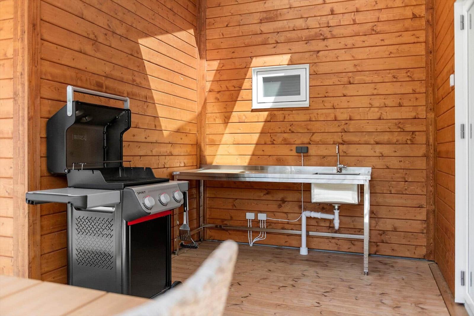 Außenküche mit Grill und Waschbecken an Holzwand