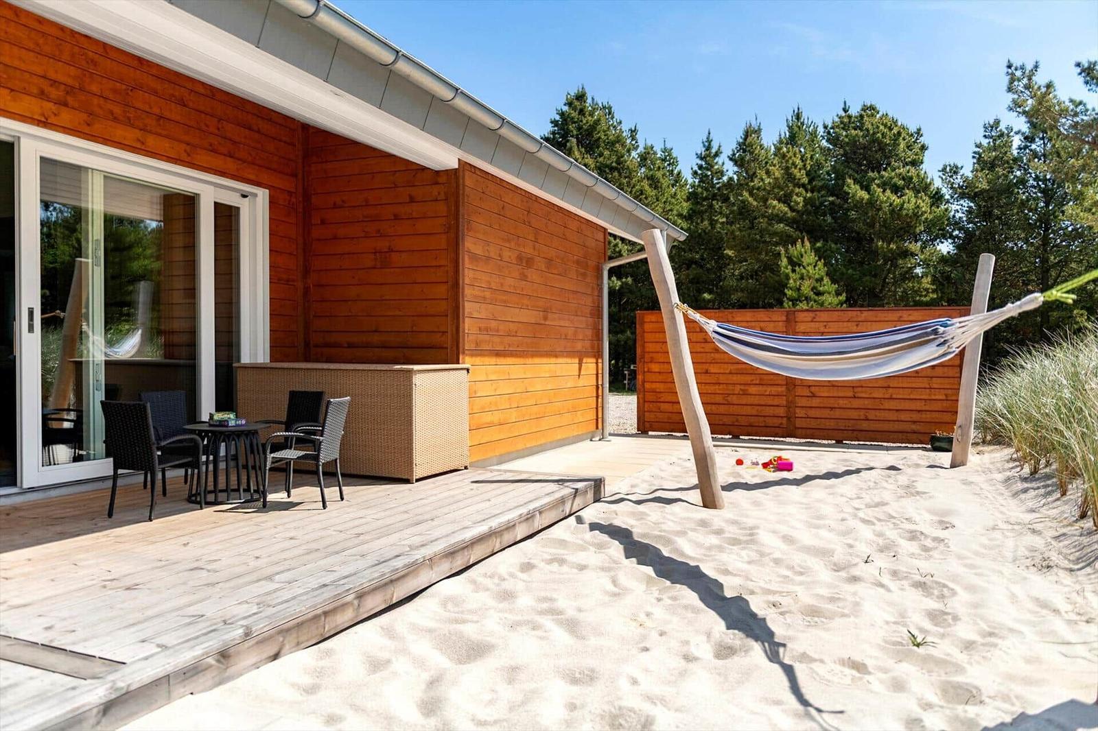 Haus mit Terrasse, Strand und Hängematte im Hintergrund.