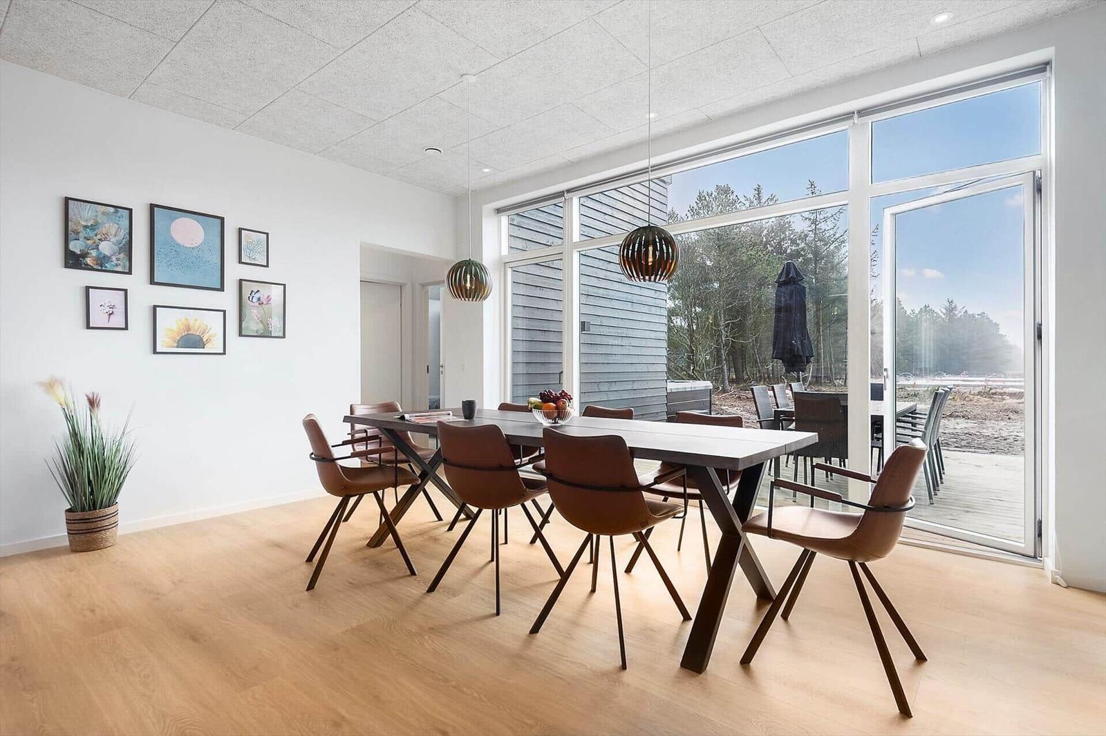 Esszimmer mit Tisch, Stühlen und großem Fenster zur Terrasse.