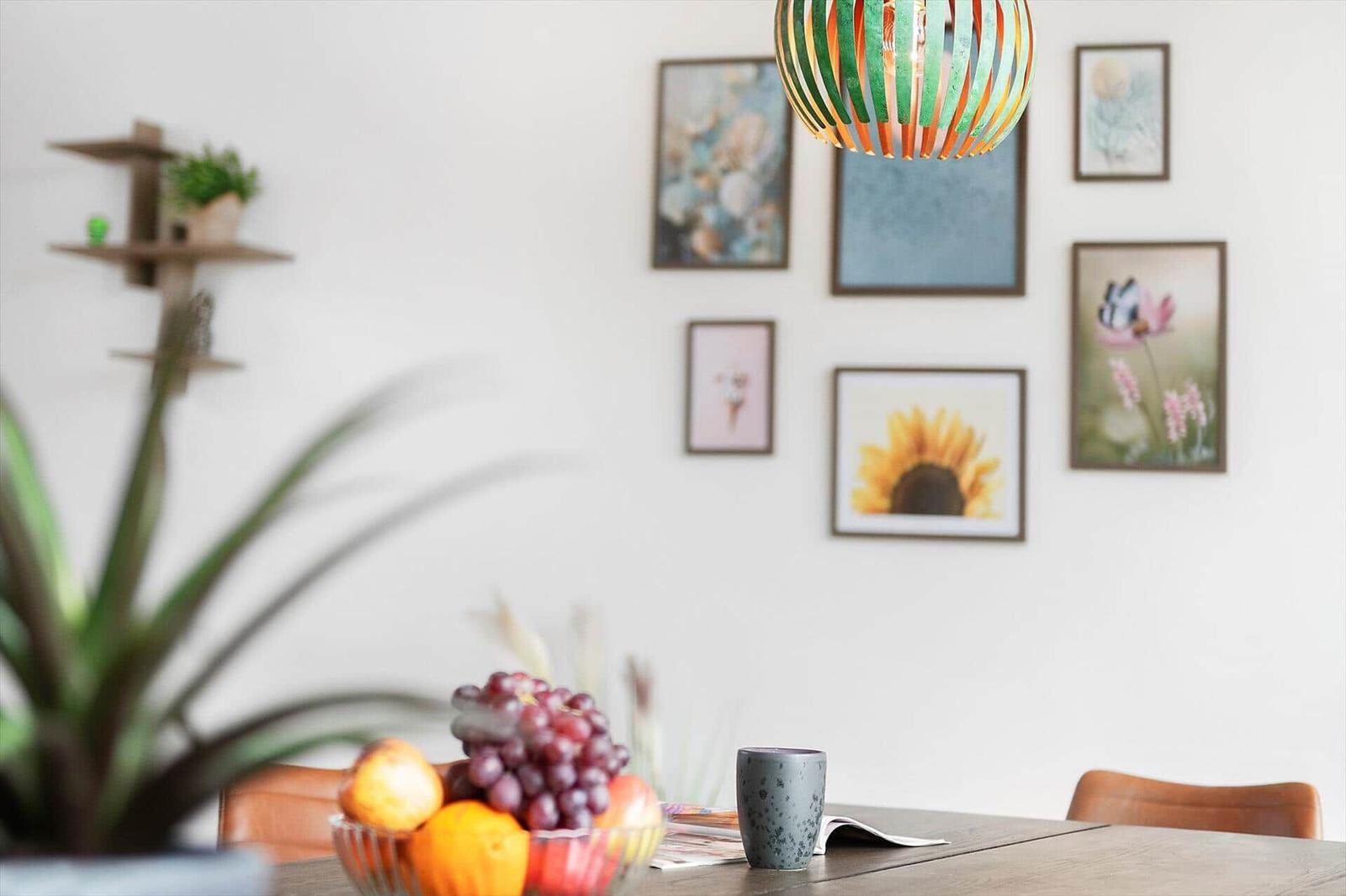 Esszimmer mit Obstschale, Wandbildern und einer hängenden Lampe.