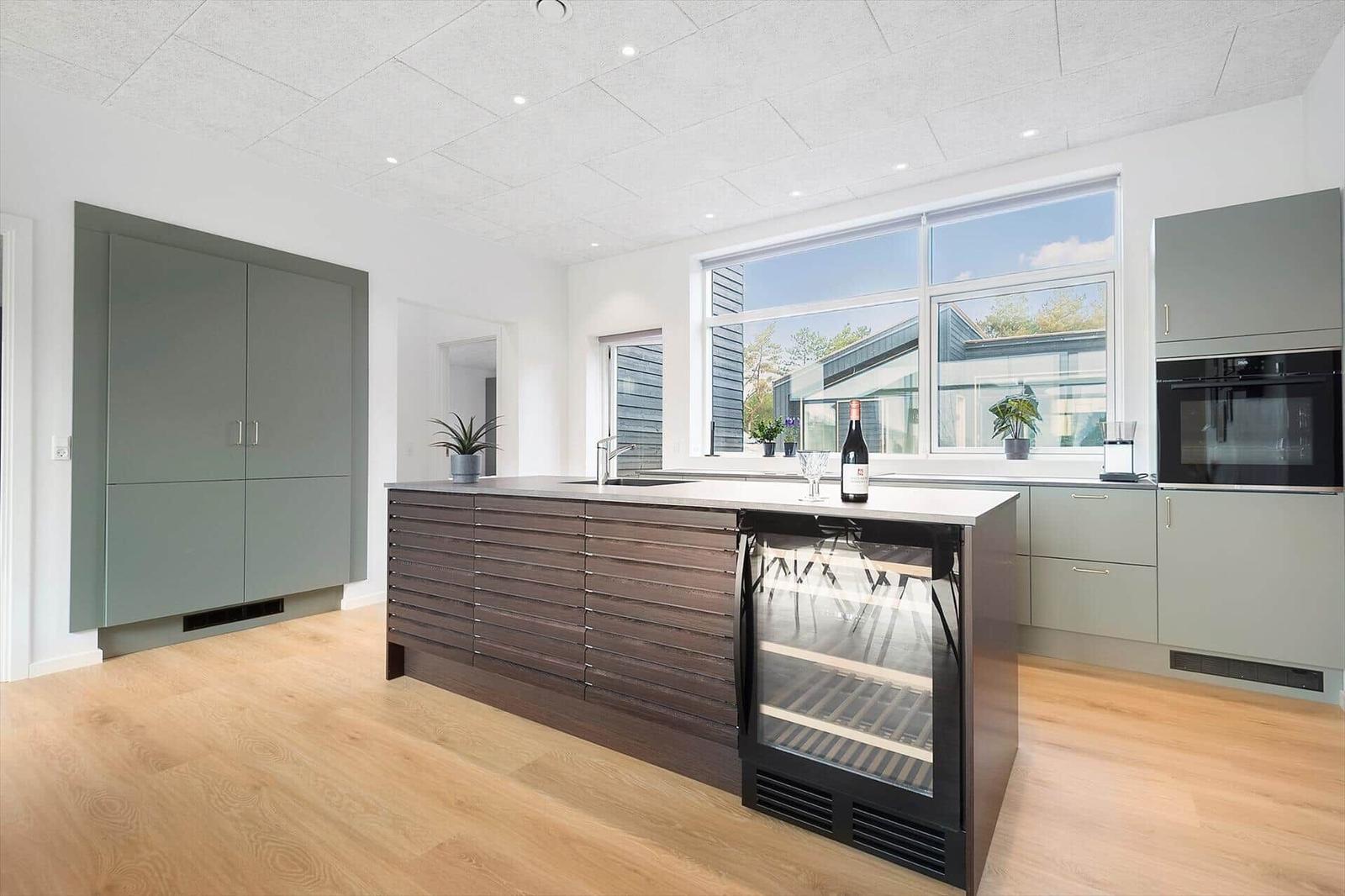 Moderne Küche mit Kücheninsel, Kühlschrank und Fenster.