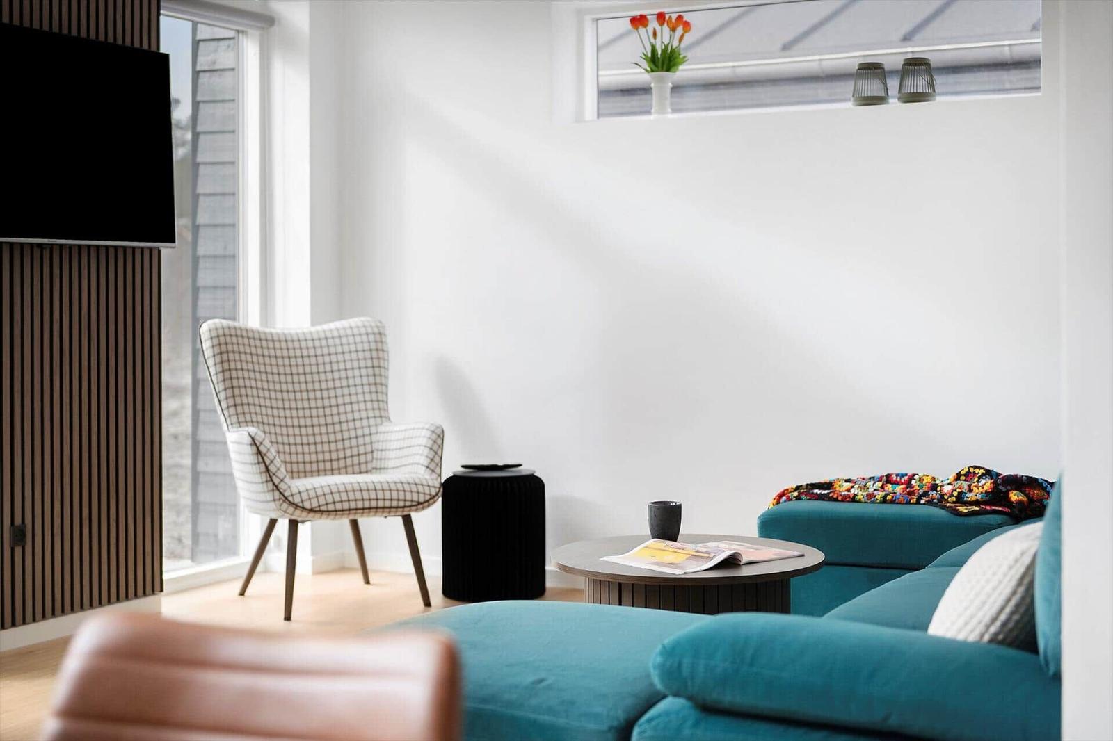 Ein Wohnzimmer mit blauem Sofa, einem Sessel und einem runden Tisch.
