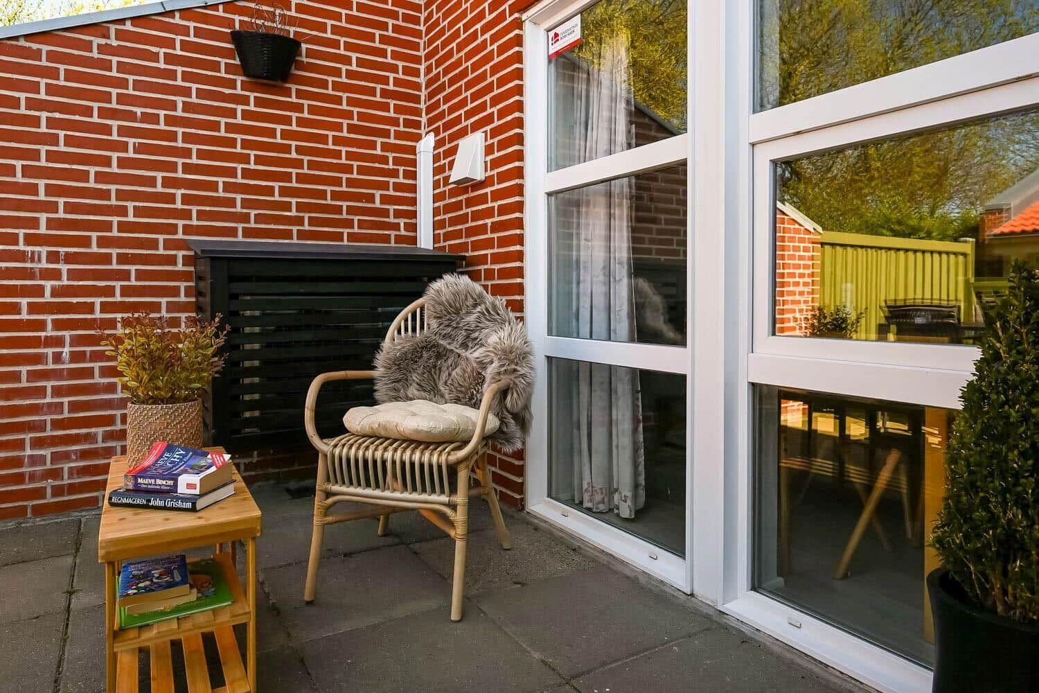 Terrasse mit Stuhl, Tisch und Pflanzen vor einer Glasfront.