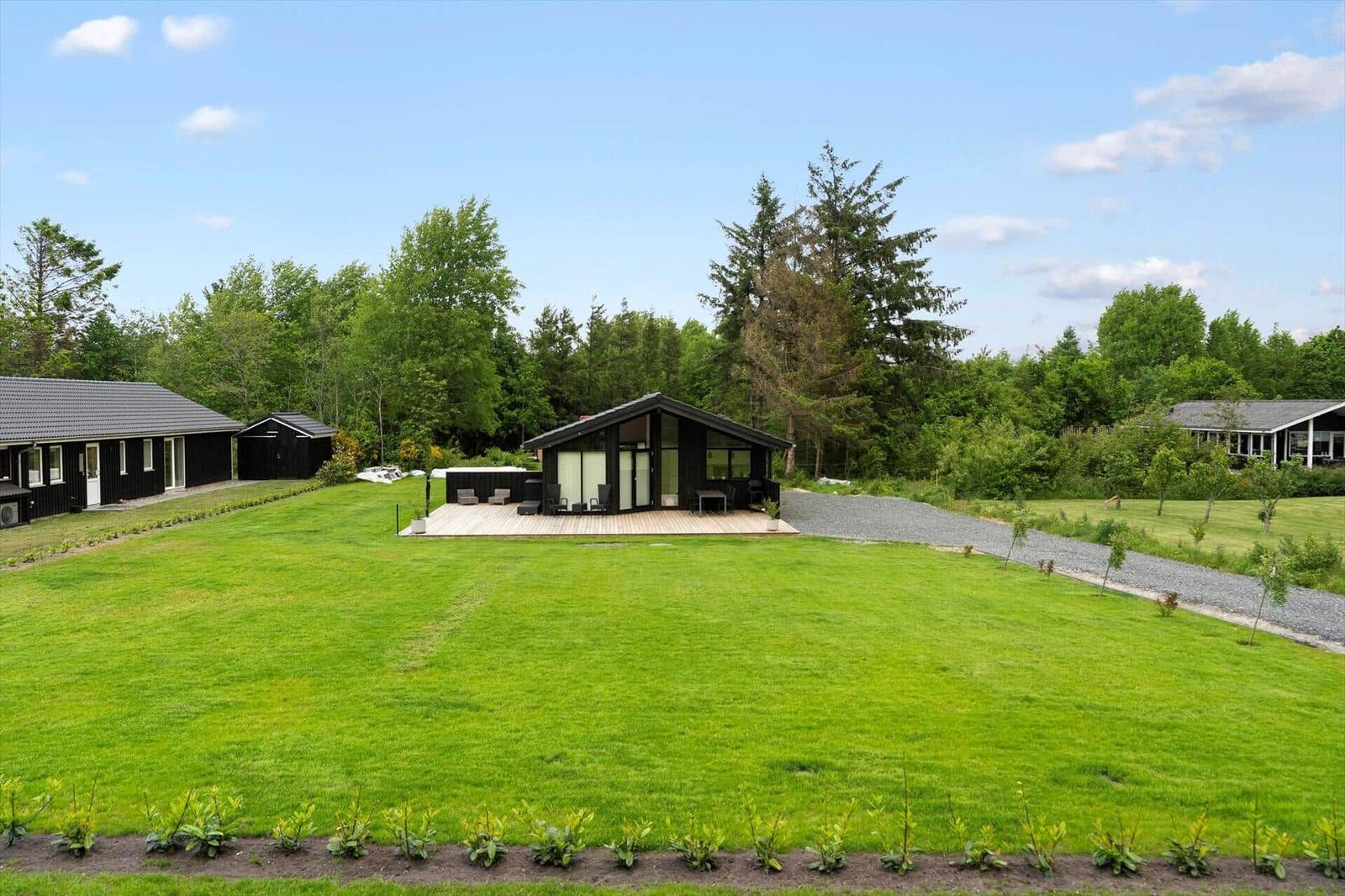 Modern wooden cabin with large garden and terrace. Surrounded by trees and greenery.