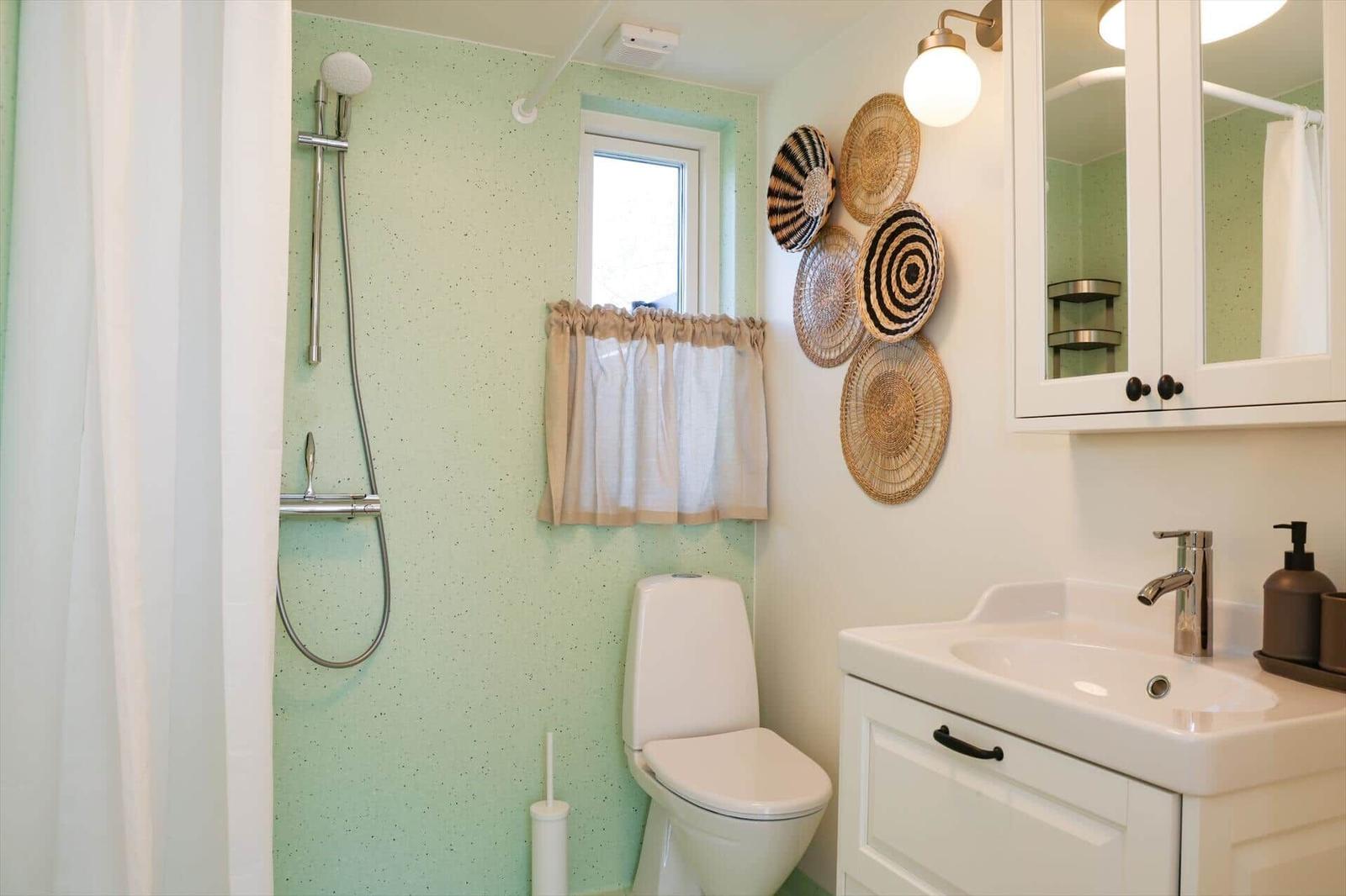 Bathroom with shower, toilet, and sink. Wall with decorative baskets.