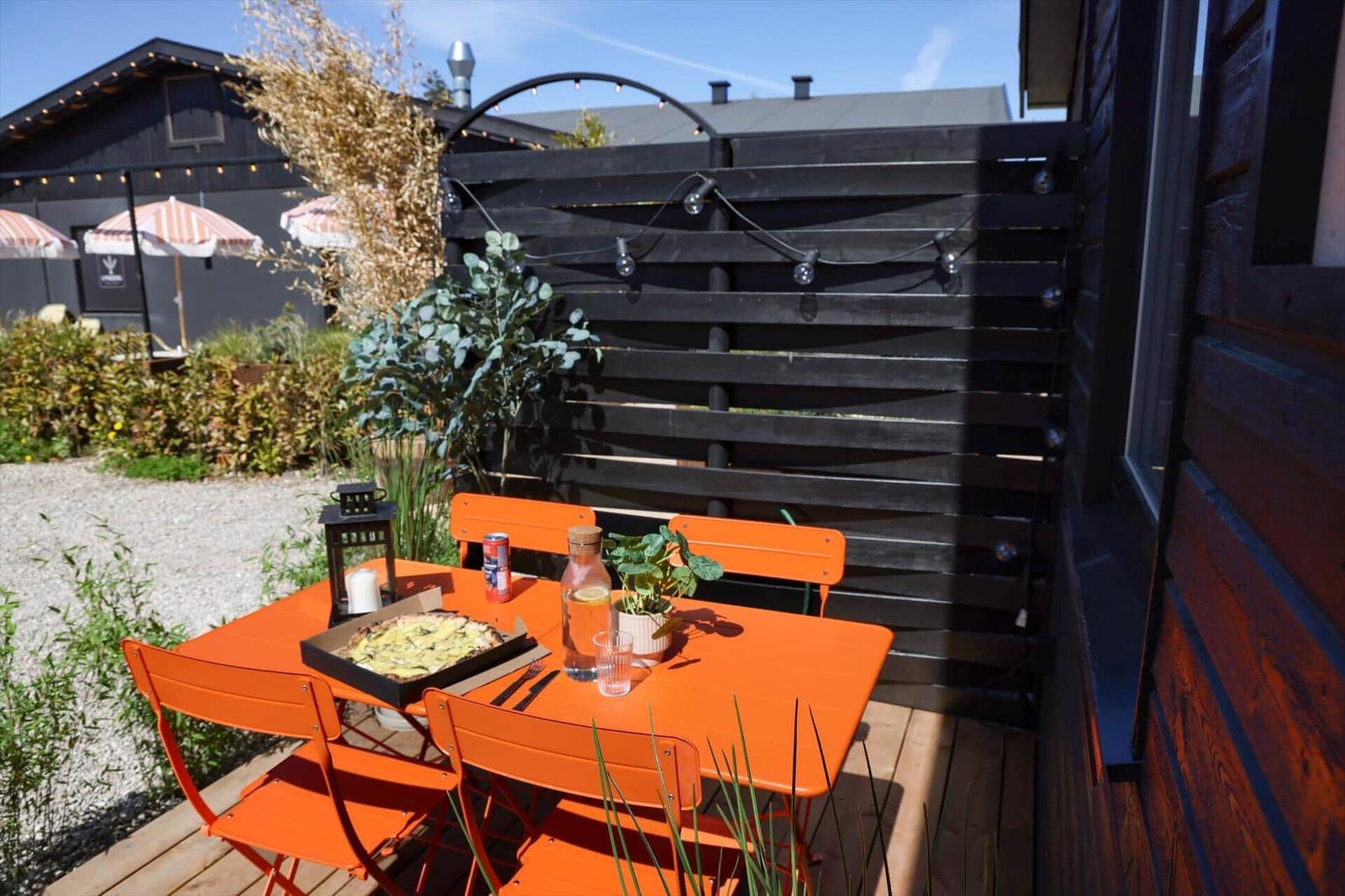 Orange table and chairs on terrace with plants and seating areas.