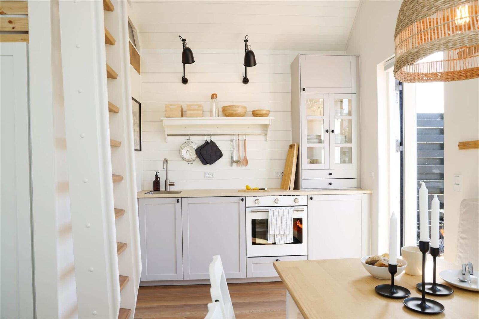 Kitchen with white cabinets, wooden countertop, and built-in oven. Table with candles and view to terrace.