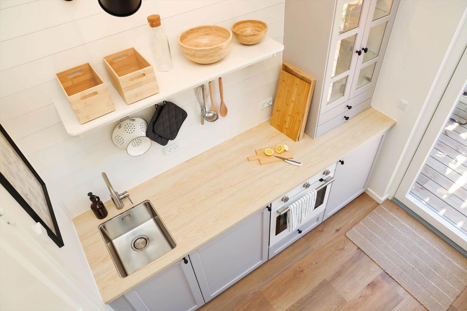 Kitchen with wooden countertop, sink, stove, and cabinets. On the countertop are lemons and a knife.