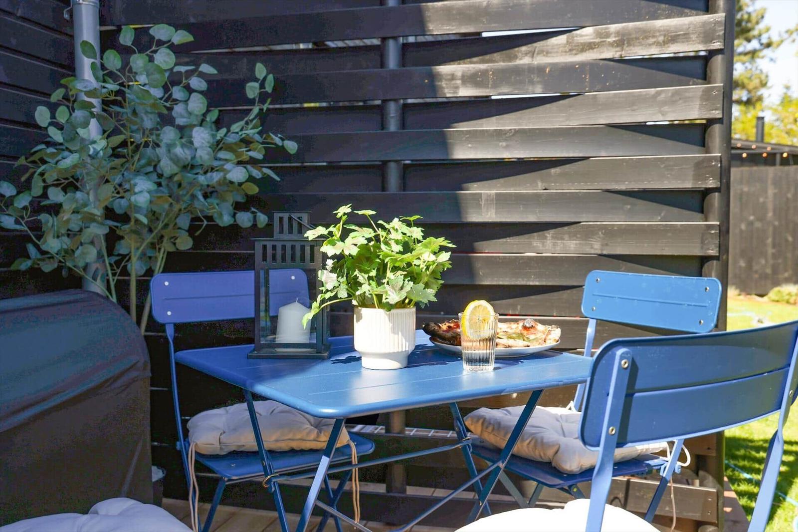 Blue table and chairs with plants and food in the garden.