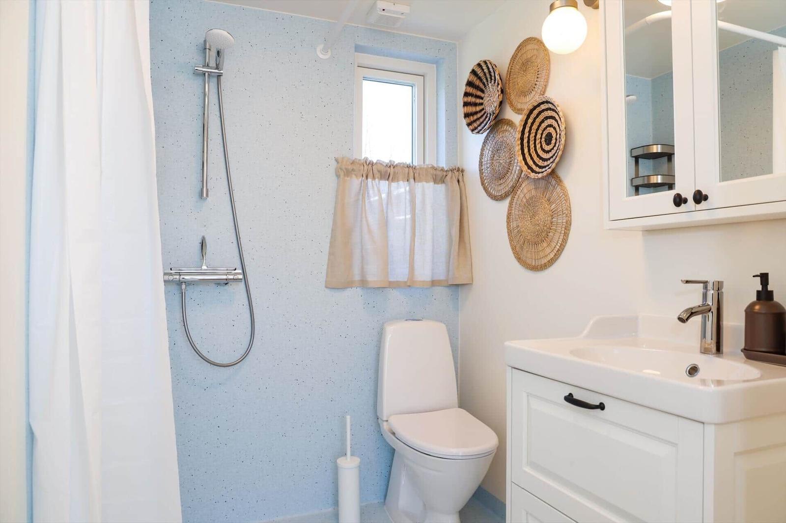 Bathroom with shower, toilet, and sink. Wall with basket decor.