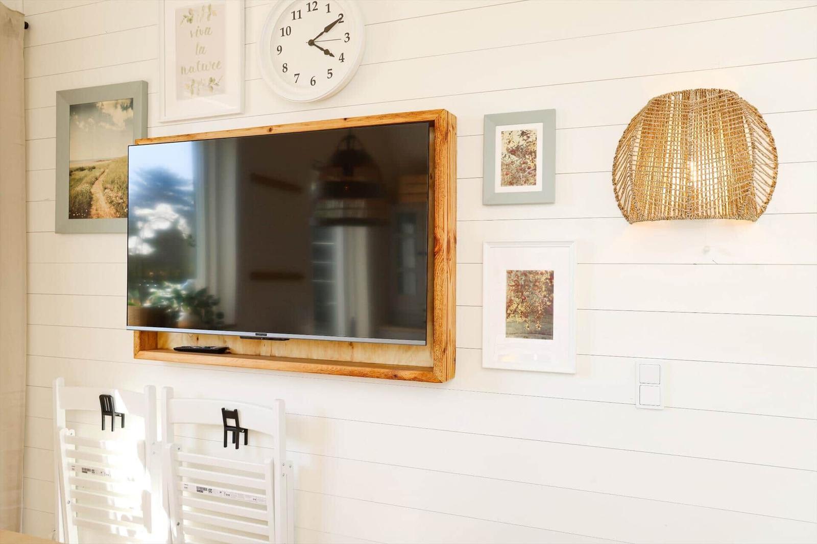 Wall with TV, picture frames, and round lamp shade.