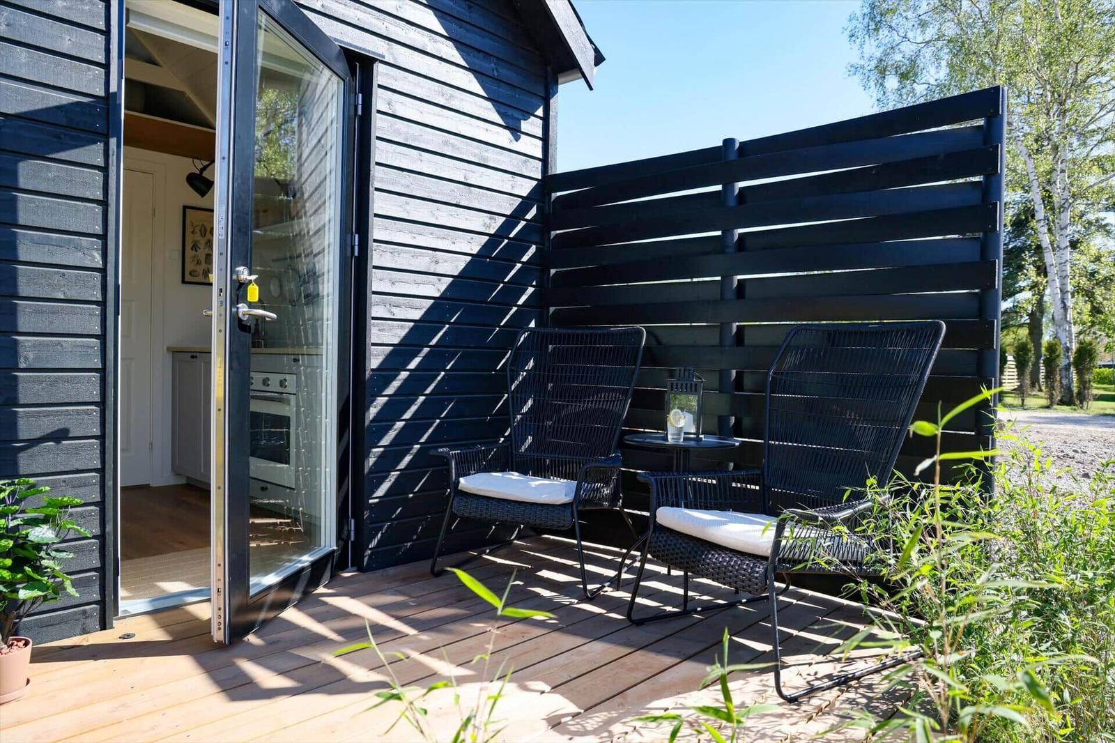 Terrace with two chairs and table. Glass door leads to interior space.