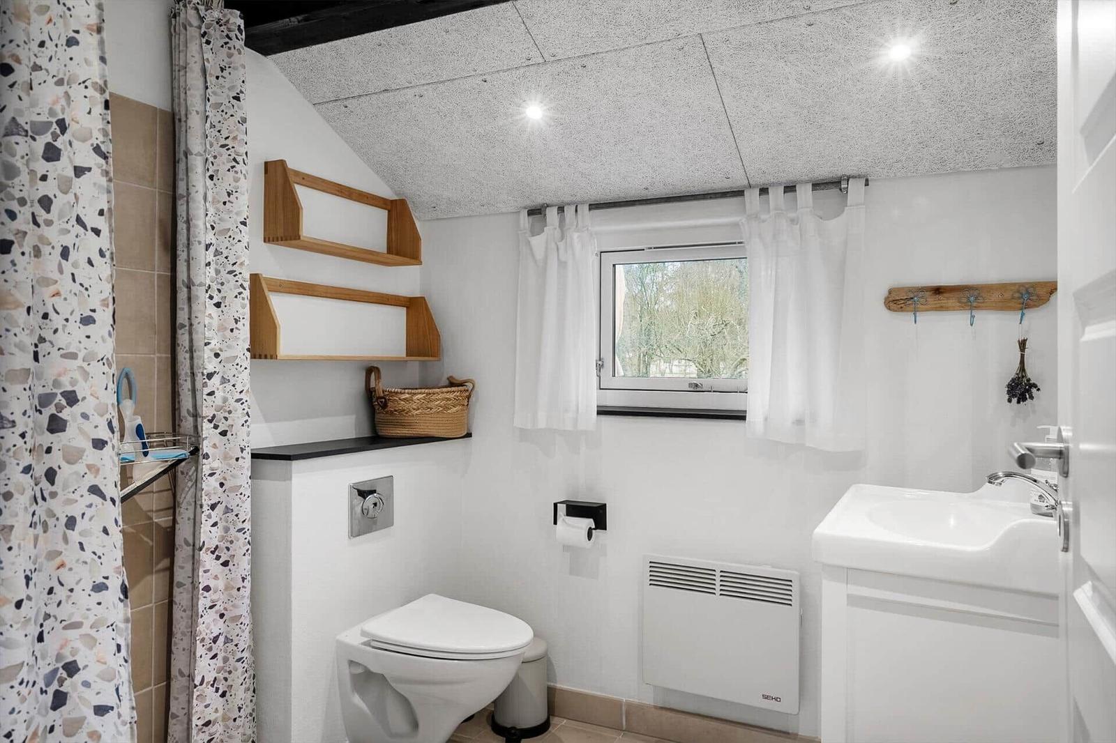 Bathroom with toilet, sink, and shower with terrazzo bathtub.