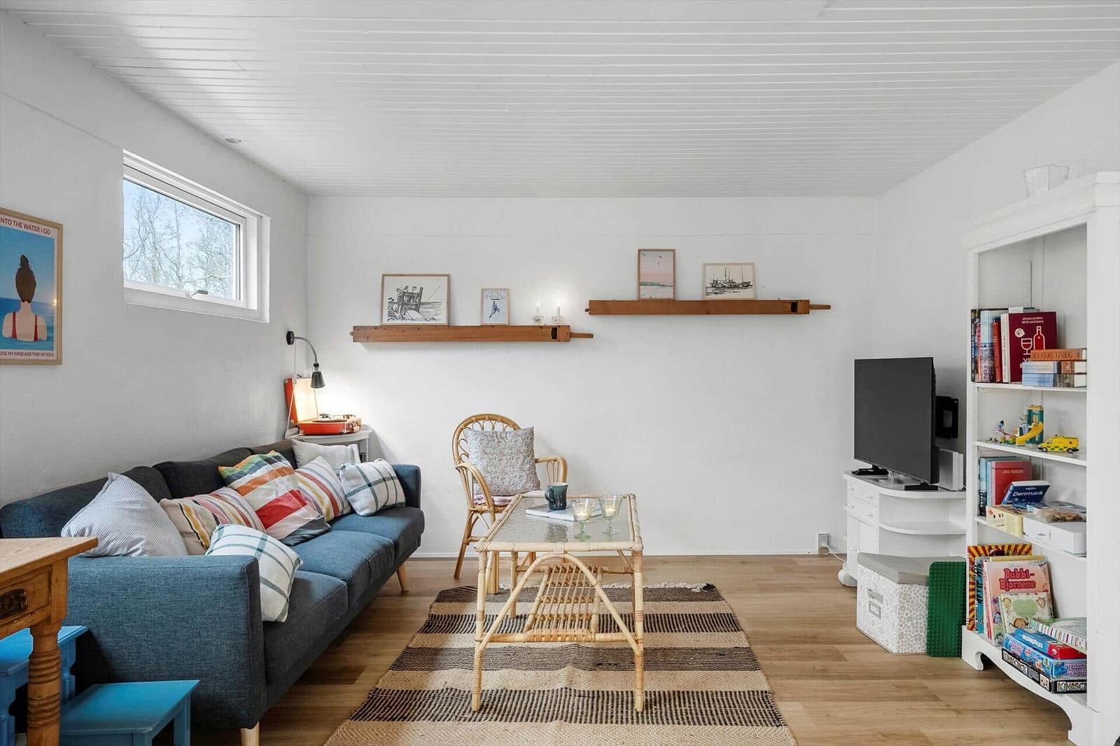 Living room with sofa, coffee table, and bookshelf. Wooden floors and white walls.