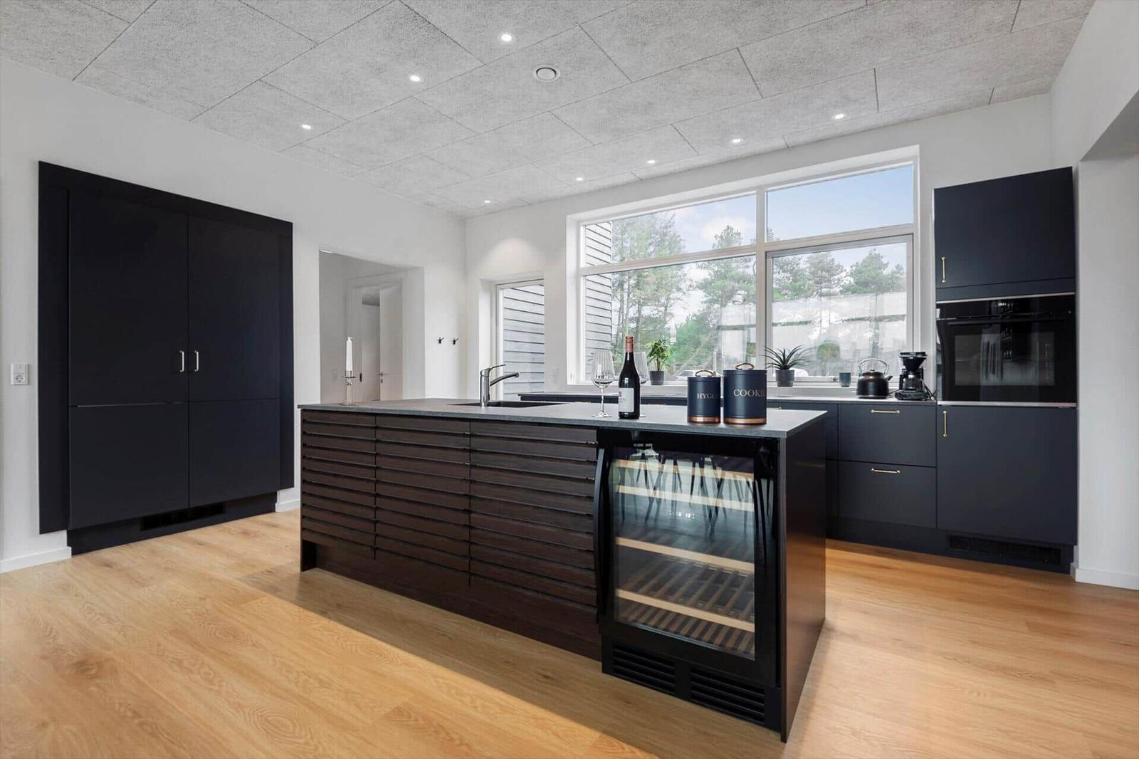 Moderne Küche mit Kücheninsel, integriertem Kühlschrank und großem Fenster.