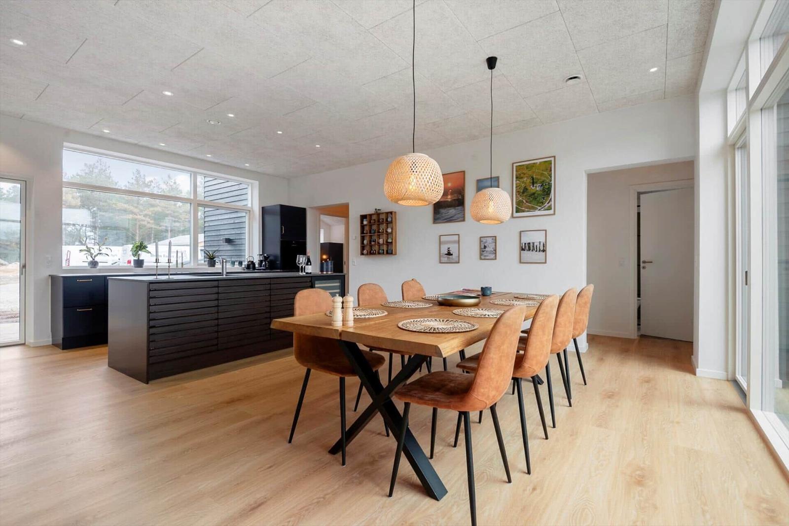 Esszimmer mit Holztisch, orangefarbenen Stühlen und moderner Küchenzeile.