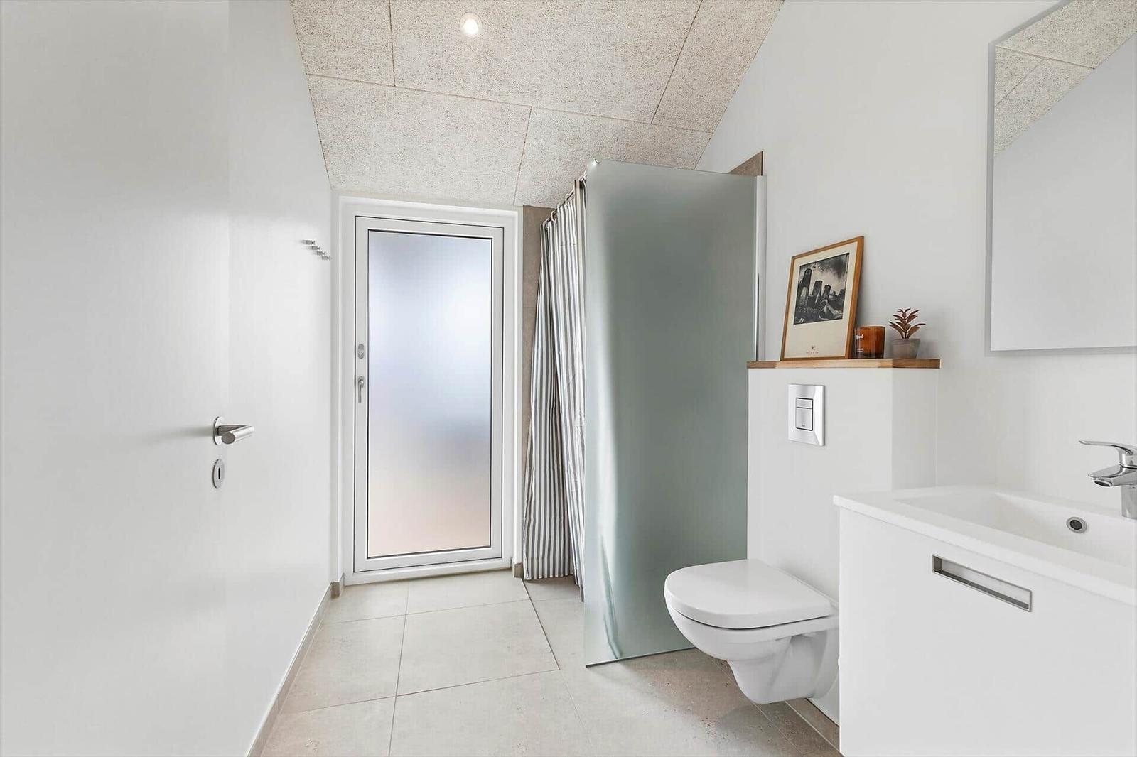 Badezimmer mit Toilette, Waschbecken und Dusche mit Glaswand.