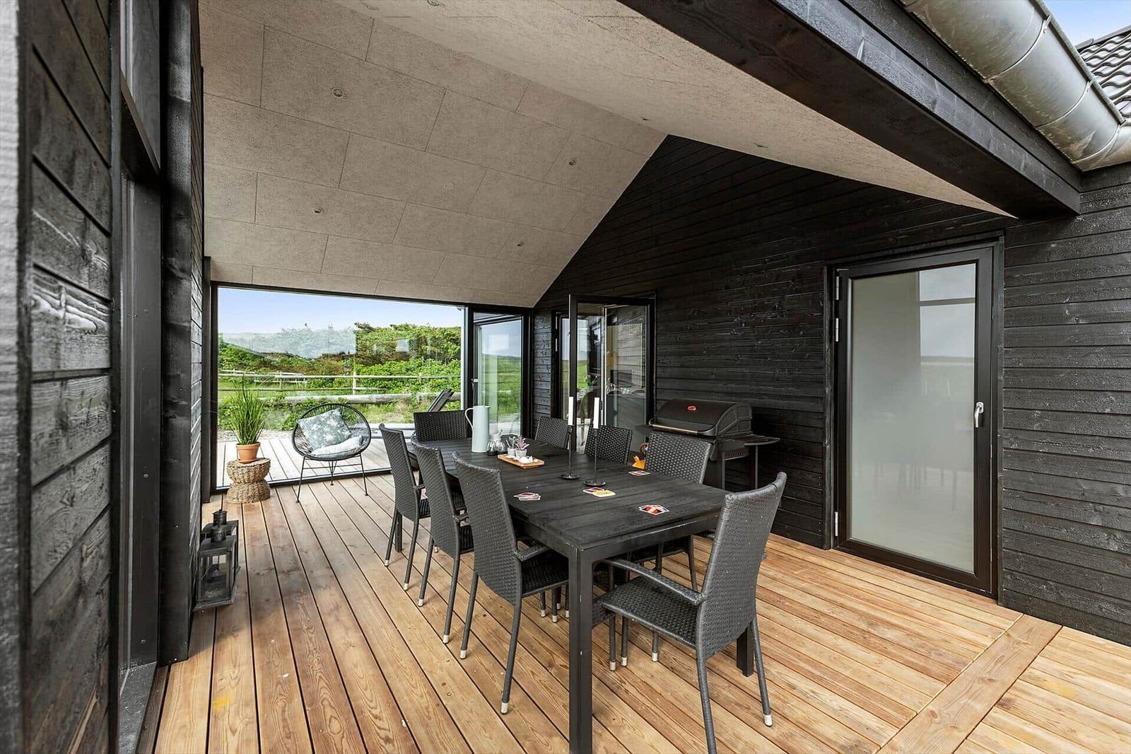 Terrasse mit Essbereich, Grill und Blick auf Landschaft.
