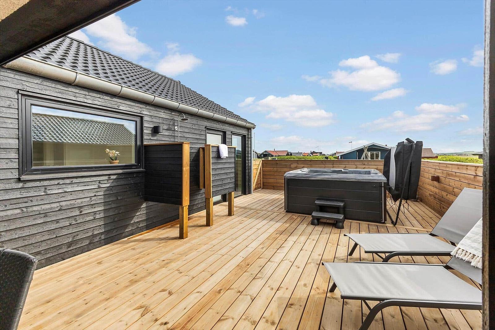 Terrasse mit Whirlpool, Liegestühlen und Holzverkleidung. Blick auf die Umgebung.