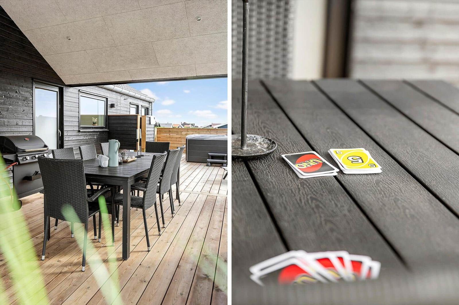 Terrasse mit Grill, Tisch und Stühlen. Spielkarten auf Tisch.