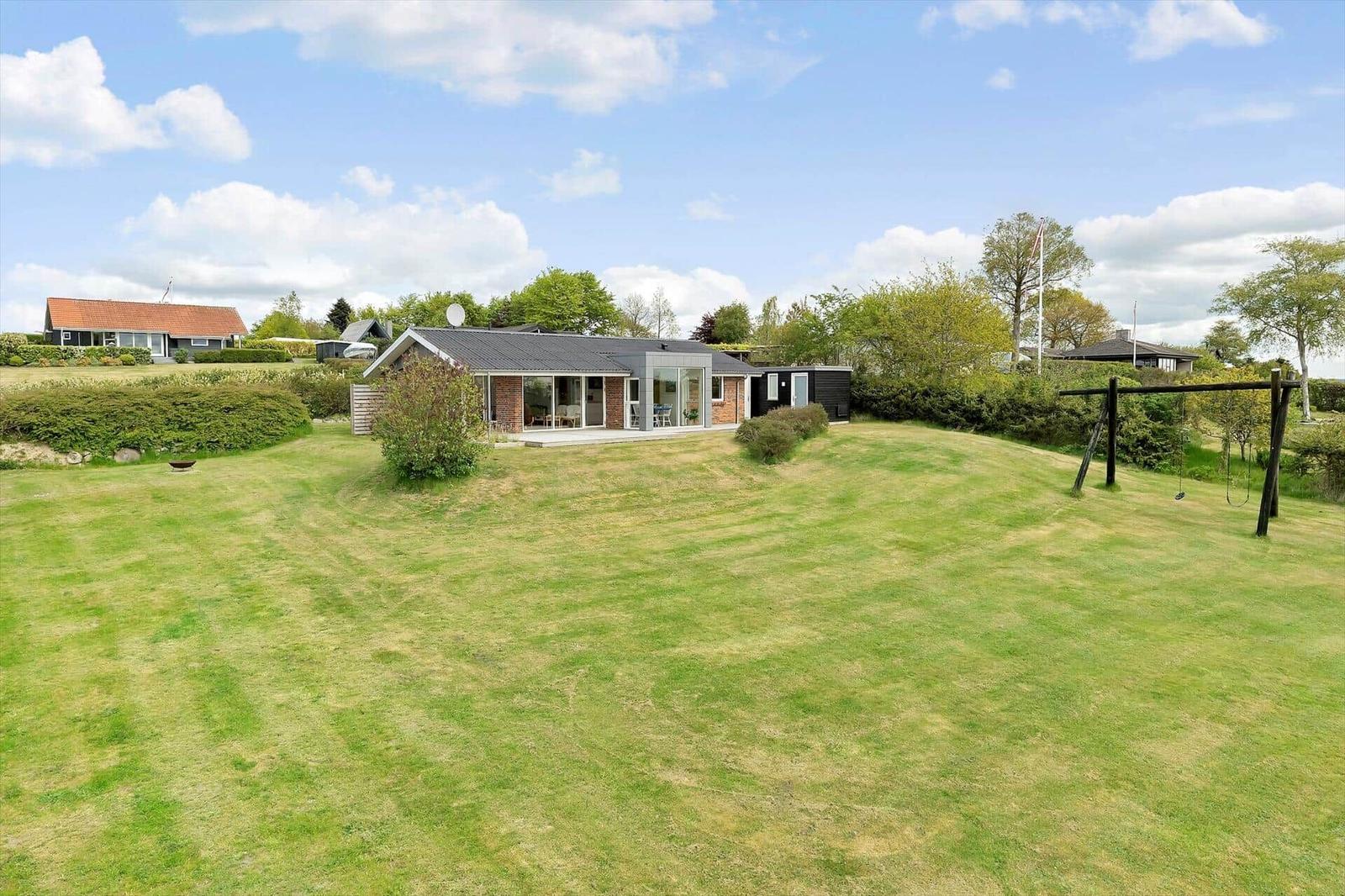 Modern villa with large garden and playground. House with glass facade and terrace.