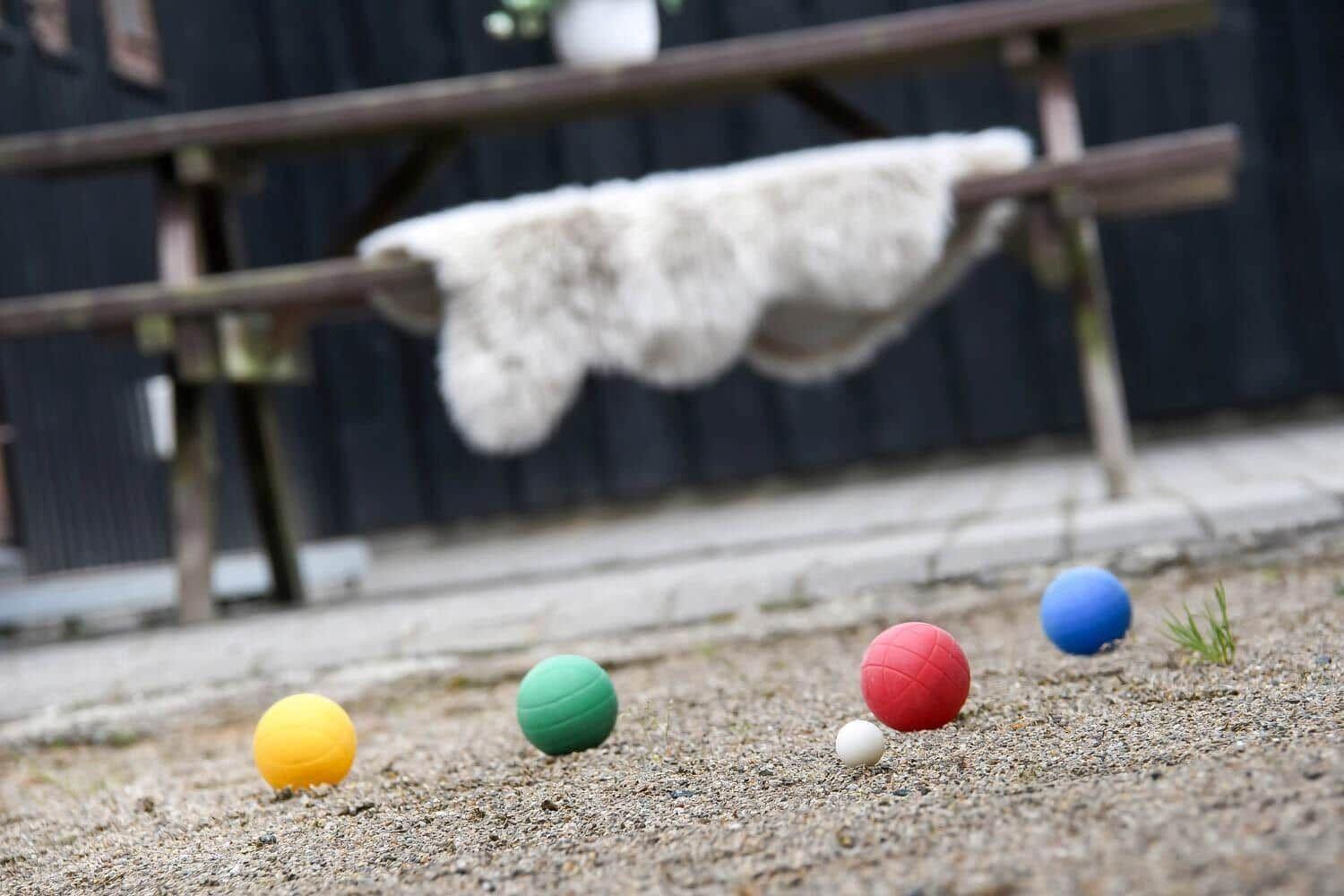 Fünf bunte Bälle liegen auf dem Boden vor einer Bank mit Decke.