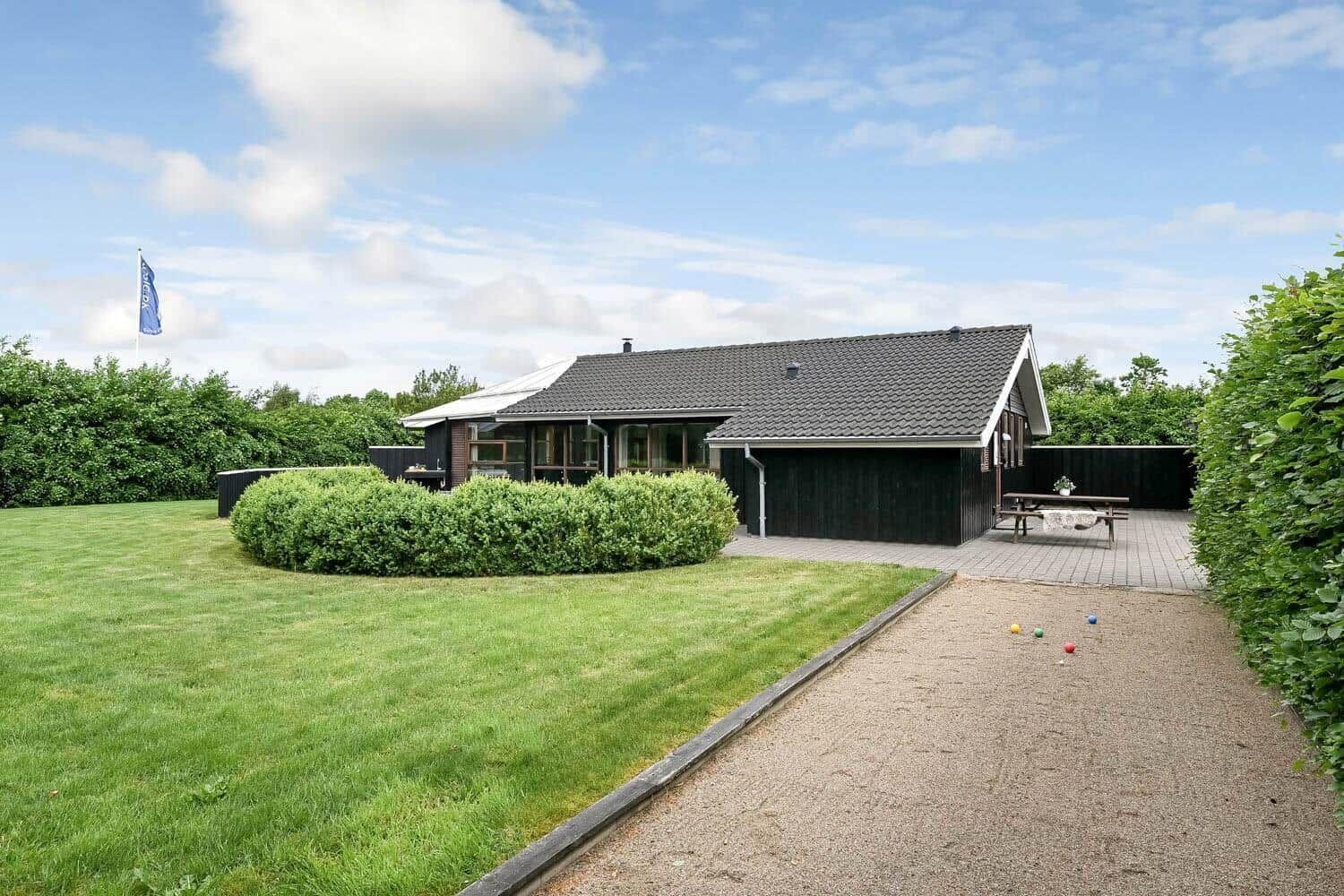 Ein Haus mit Garten, Terrasse und Grillplatz. Ein Weg führt zum Eingang.
