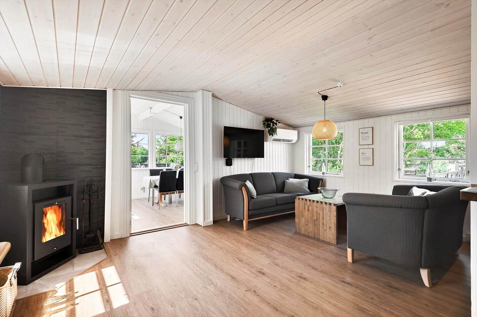 Wohnzimmer mit Kamin, Sofa und Sessel. Durchgang zum Essbereich mit Tisch und Stühlen.