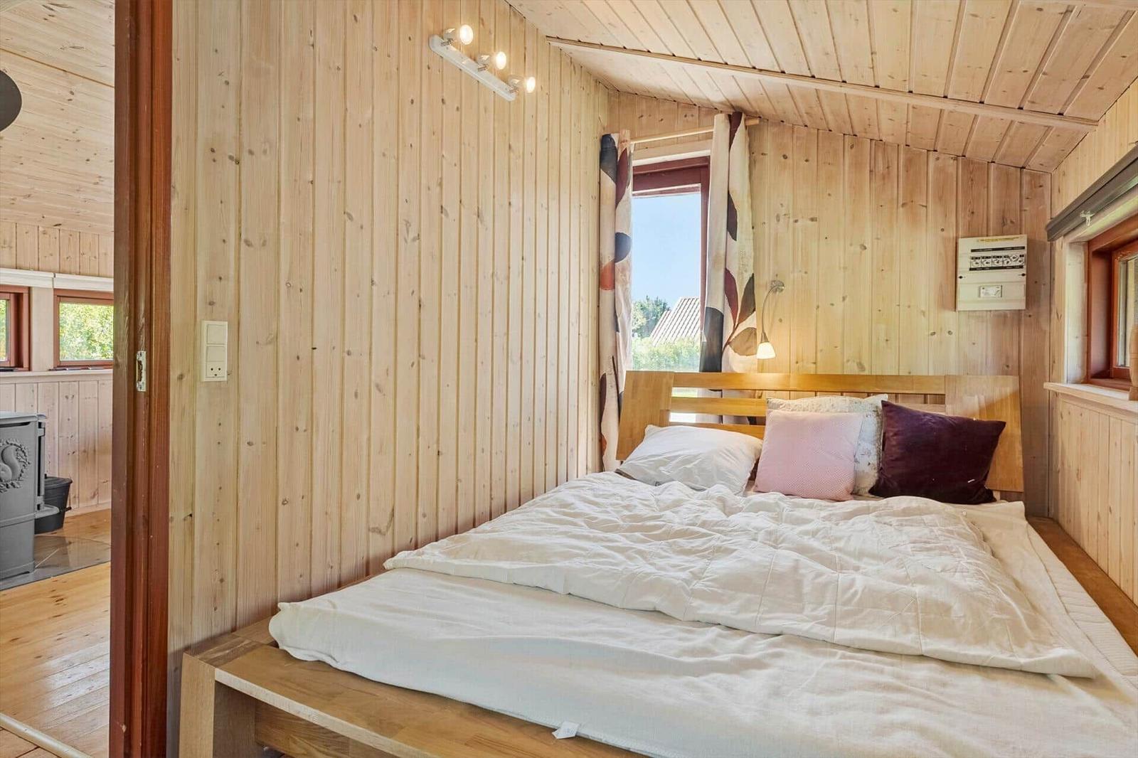 Bedroom with wooden walls and bed with pillows
